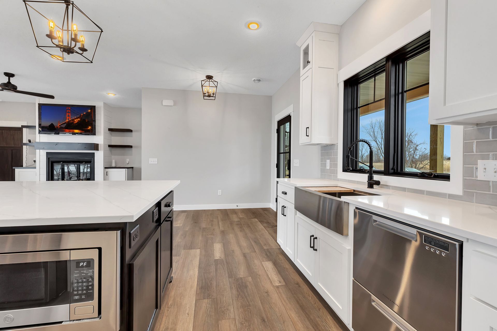 A kitchen with stainless steel appliances , white cabinets , hardwood floors and a large island.