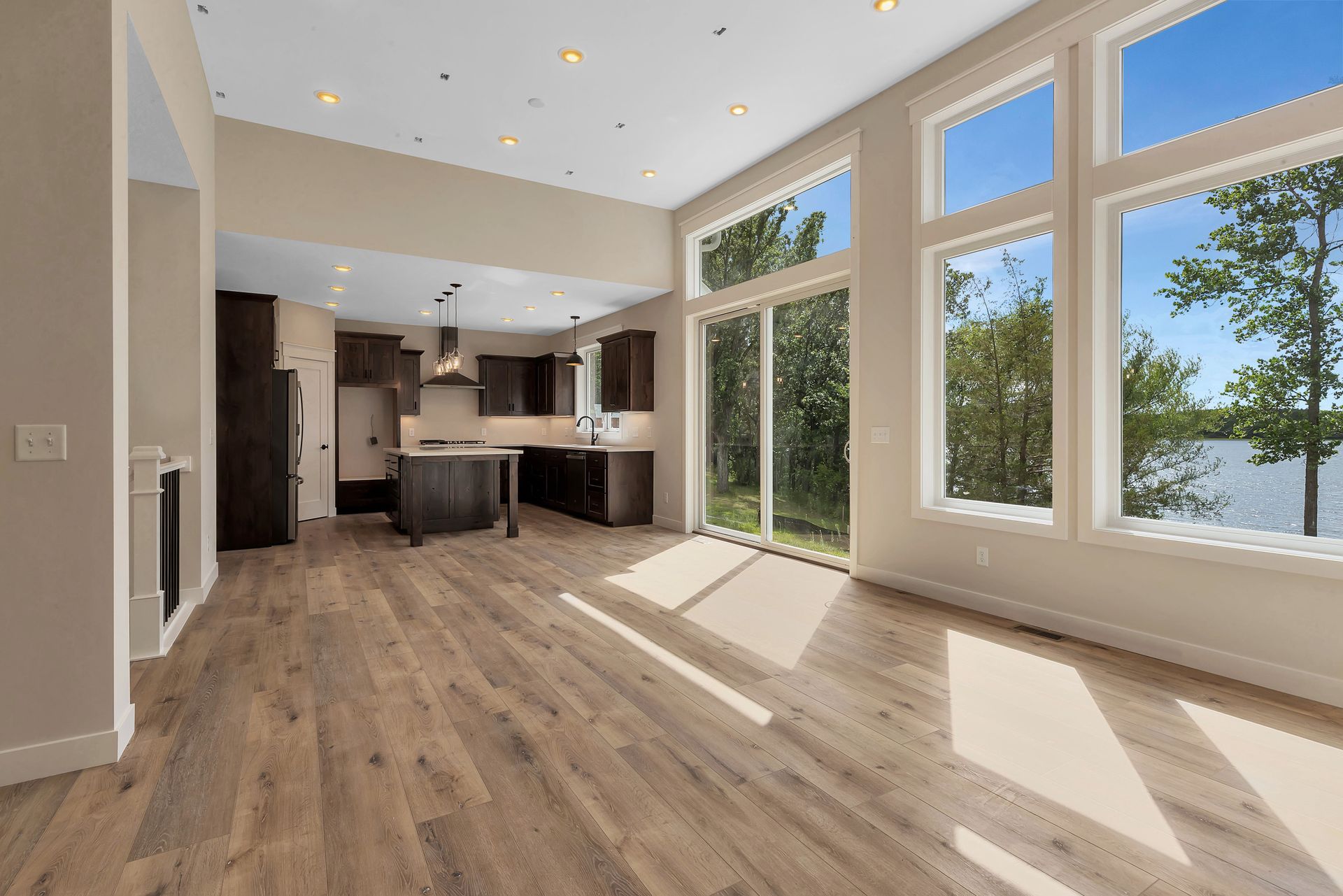 A living room with hardwood floors and lots of windows overlooking a lake.