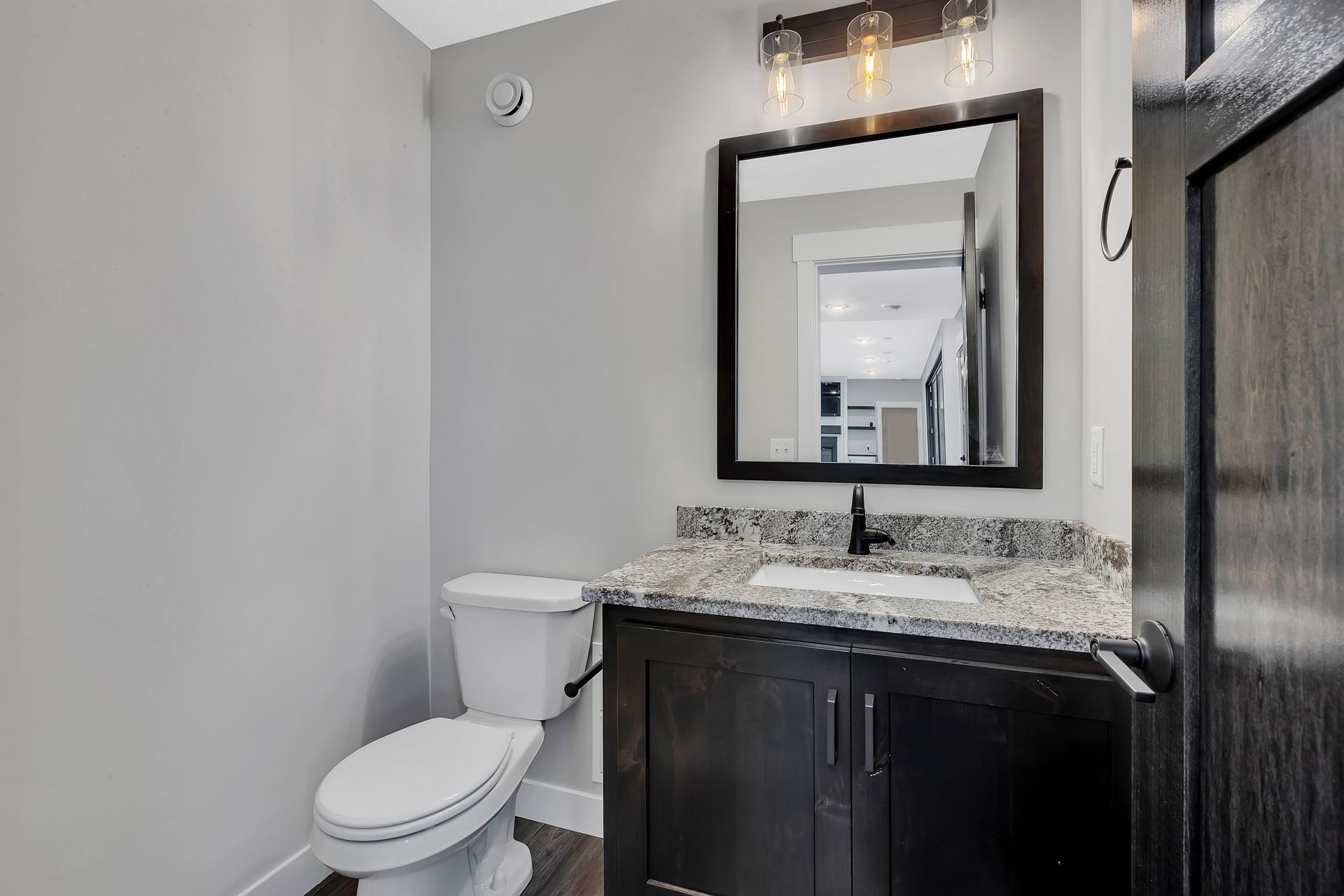 A bathroom with a toilet , sink and mirror.