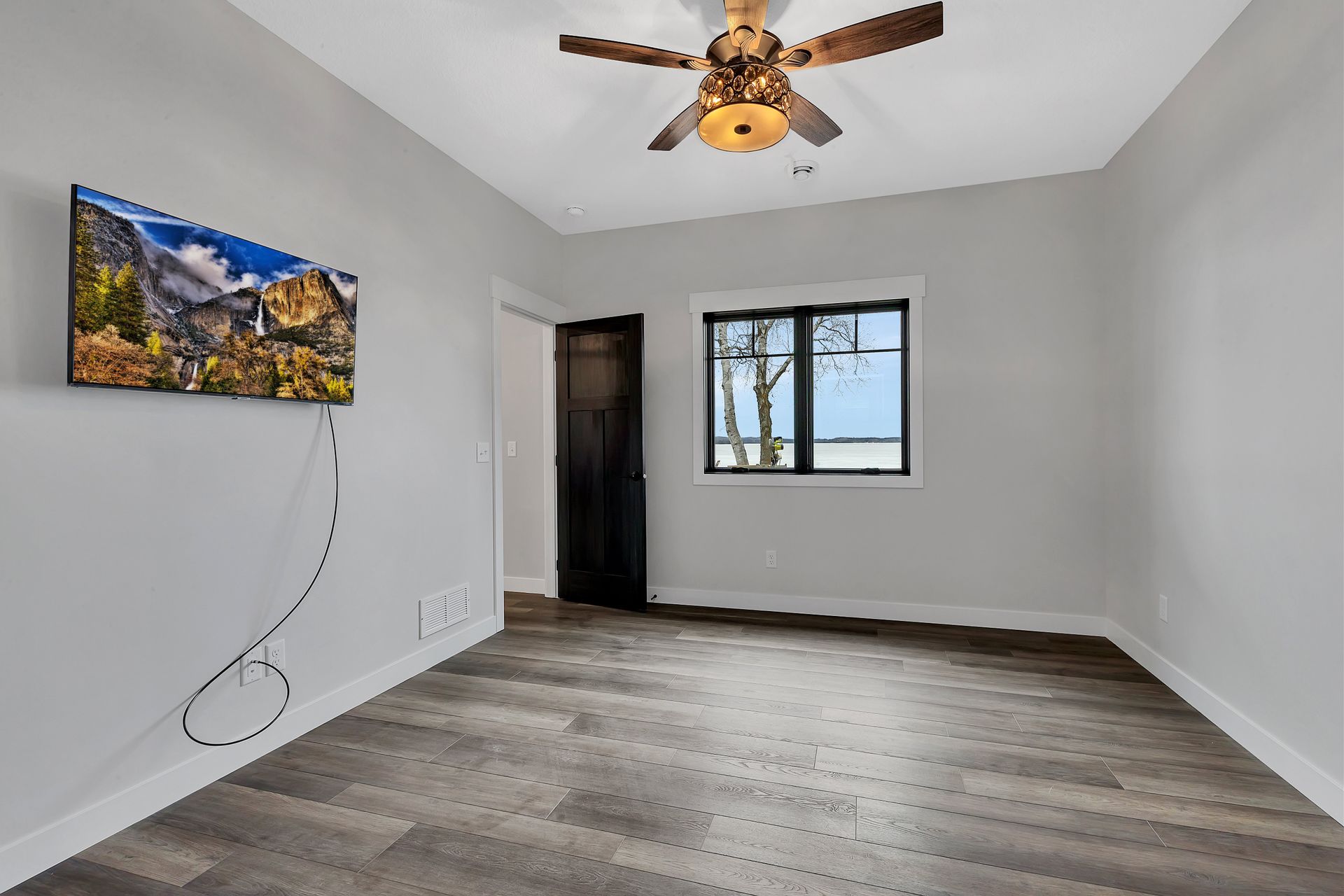 A bedroom with a ceiling fan and a flat screen tv on the wall.