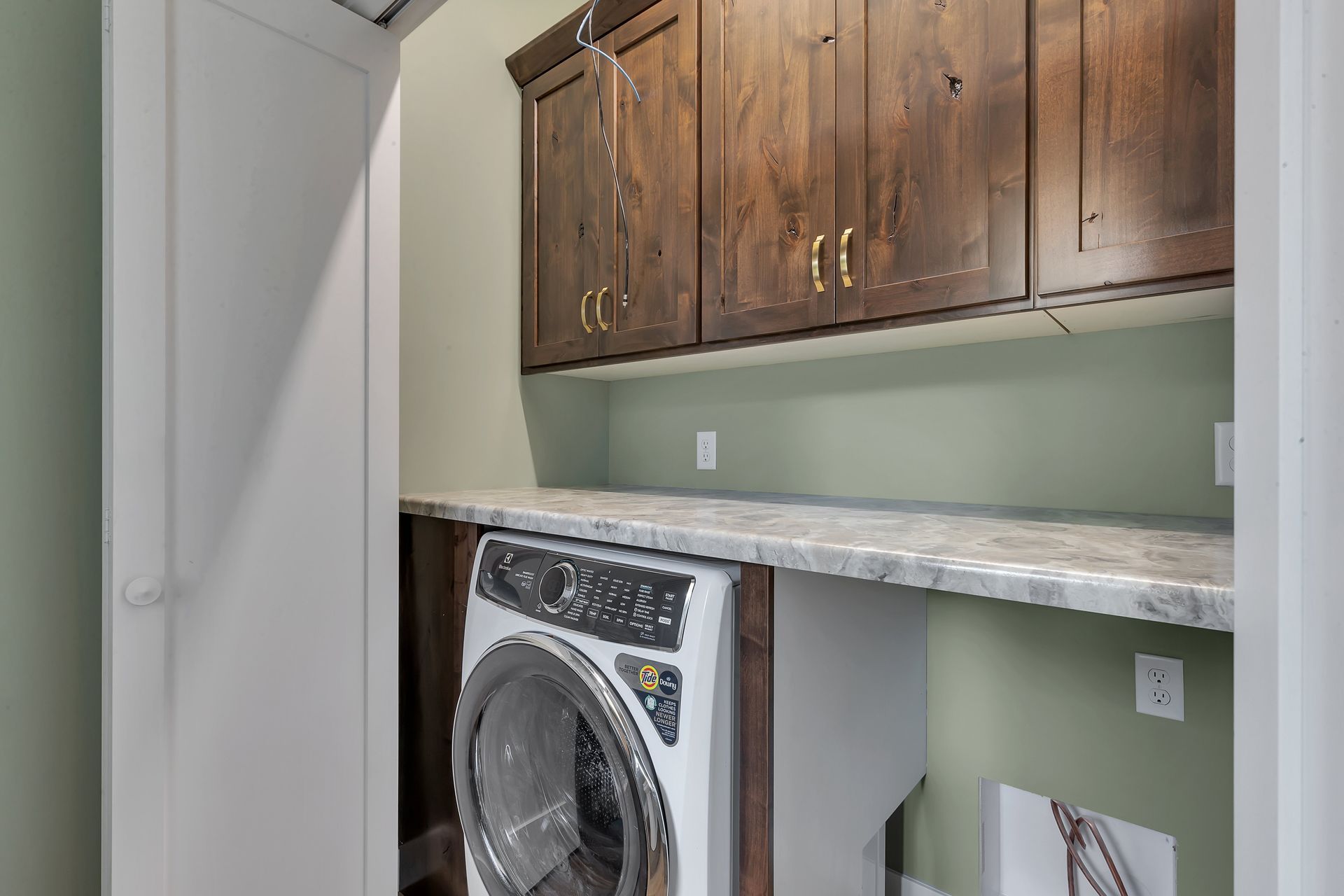 A laundry room with a washer and dryer and wooden cabinets.