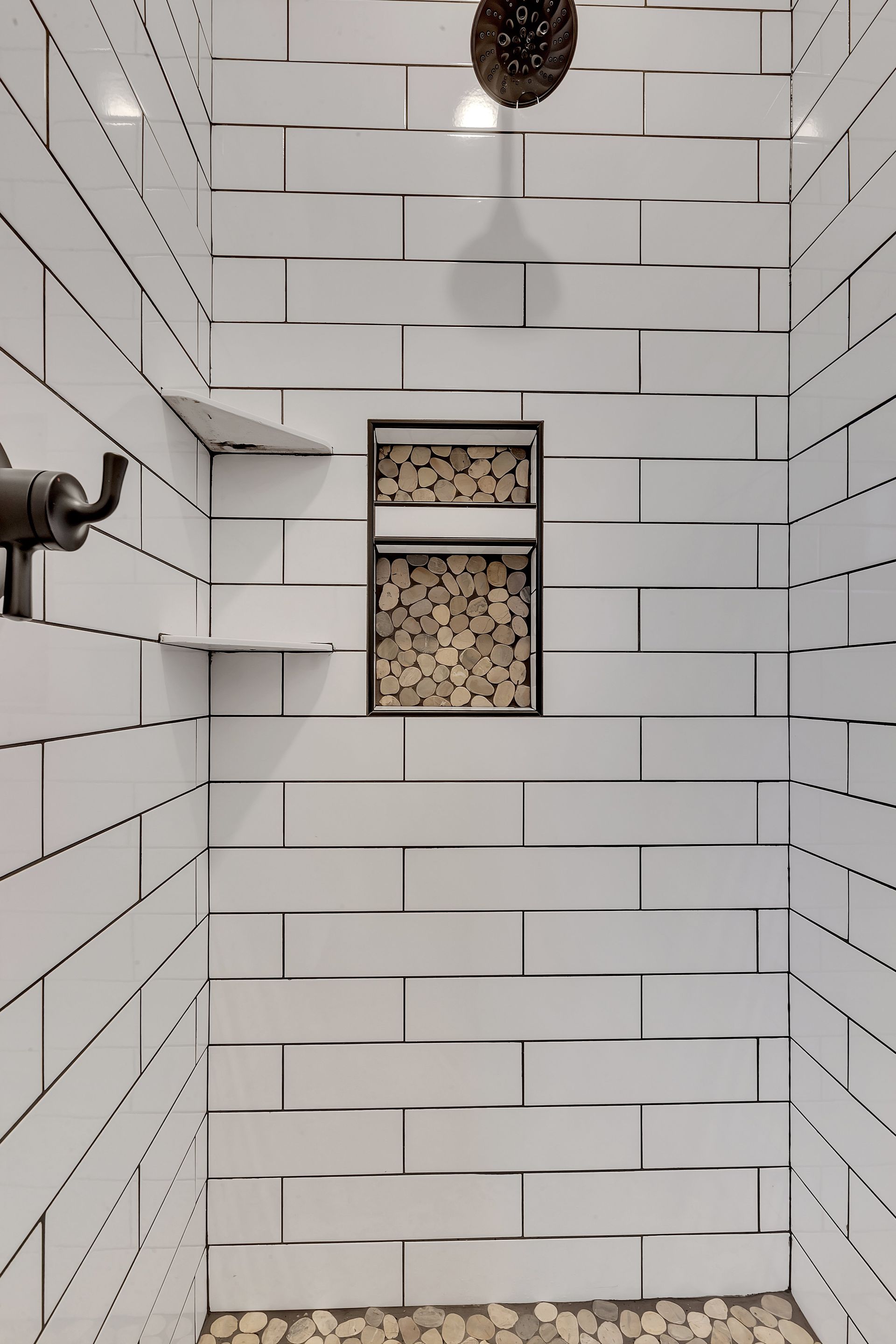 A bathroom with white brick walls and a shower head