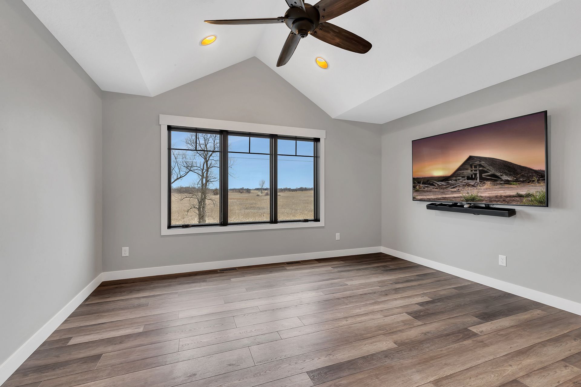 An empty room with a ceiling fan and a flat screen tv on the wall.