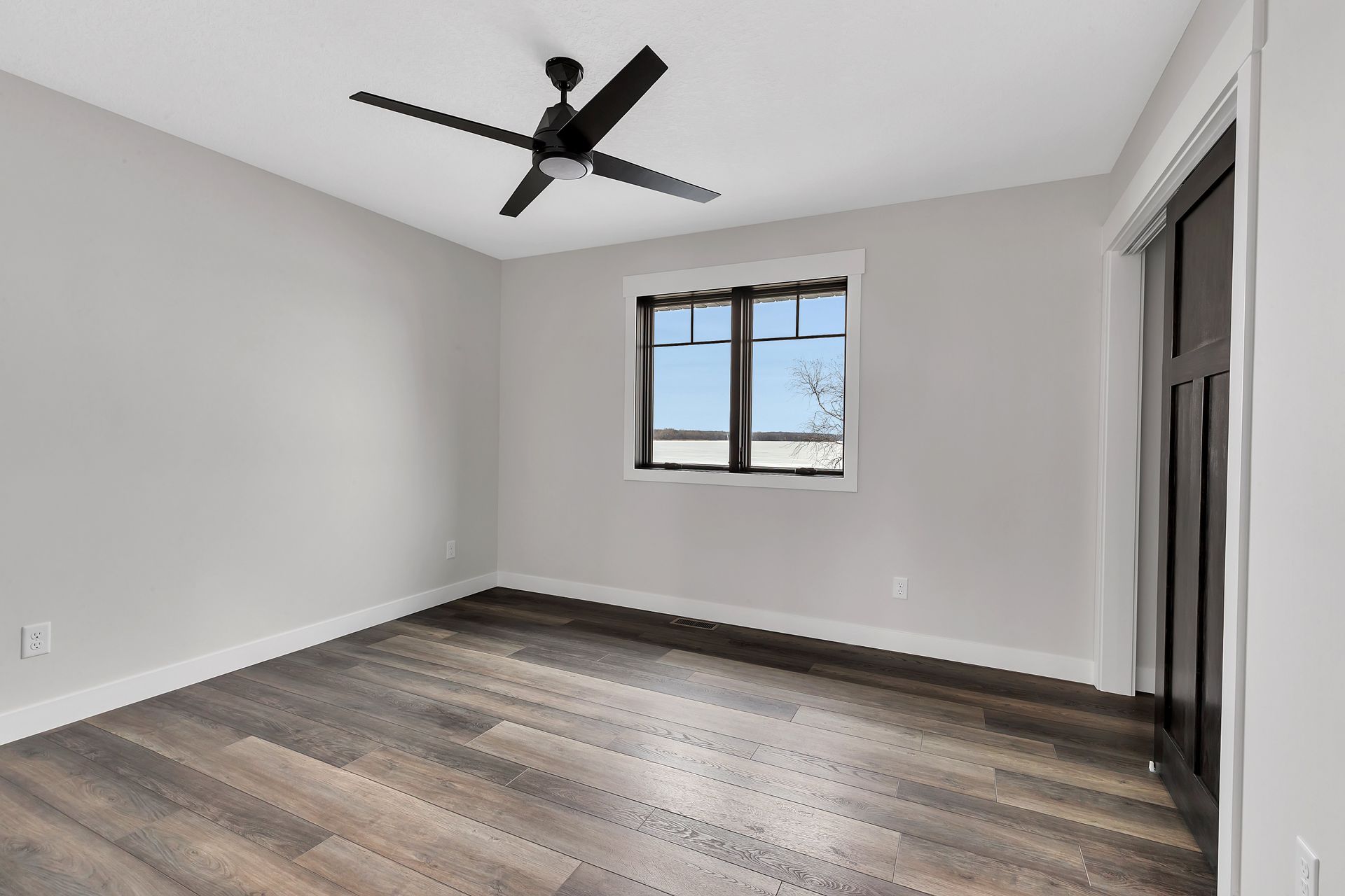 An empty room with a ceiling fan and a window.