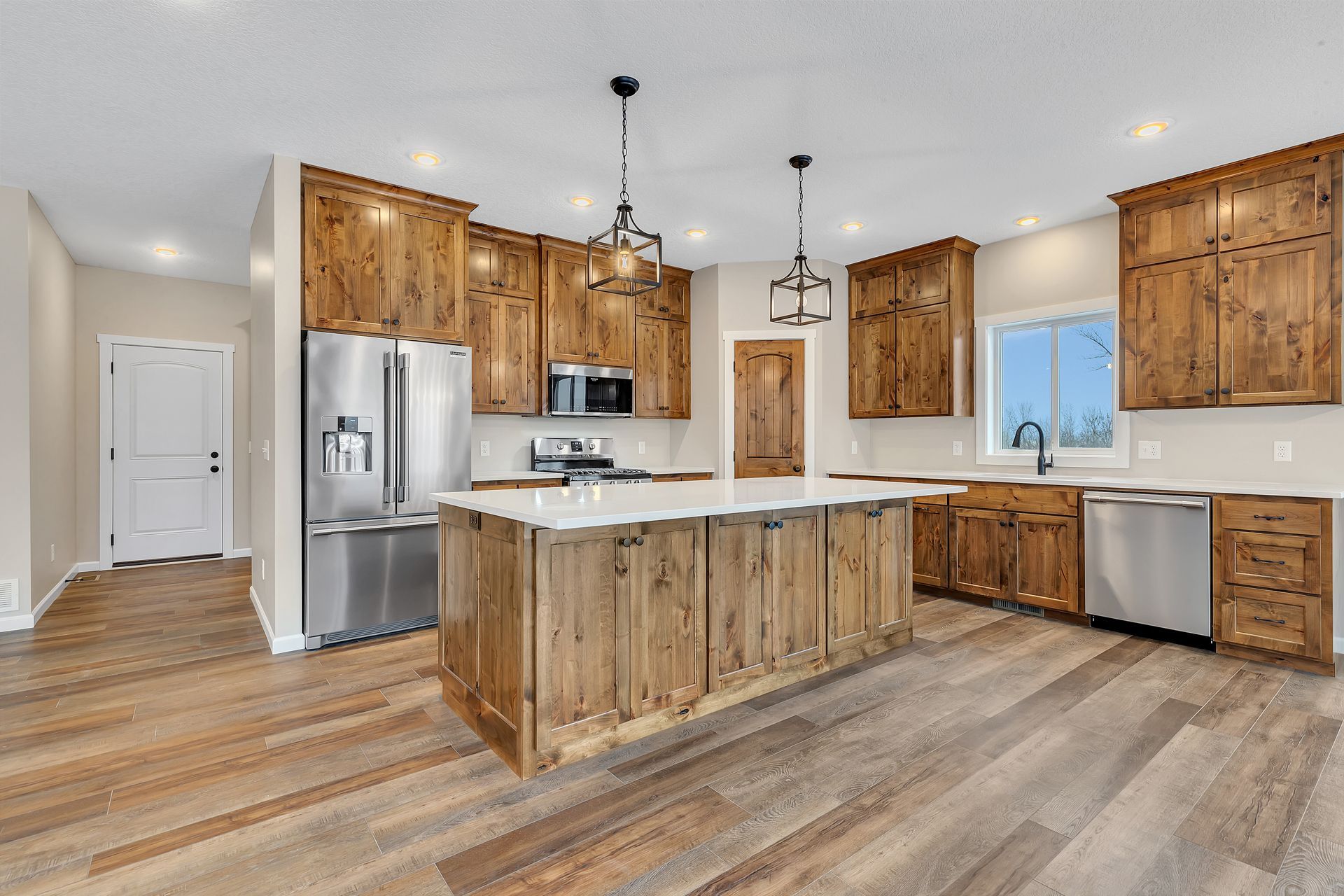 A kitchen with wooden cabinets , stainless steel appliances , and a large island.