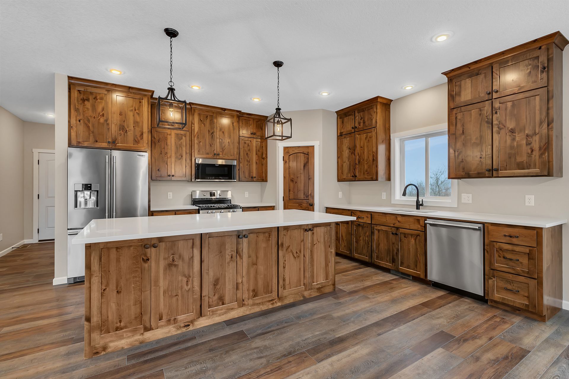 A kitchen with wooden cabinets , stainless steel appliances , and a large island.