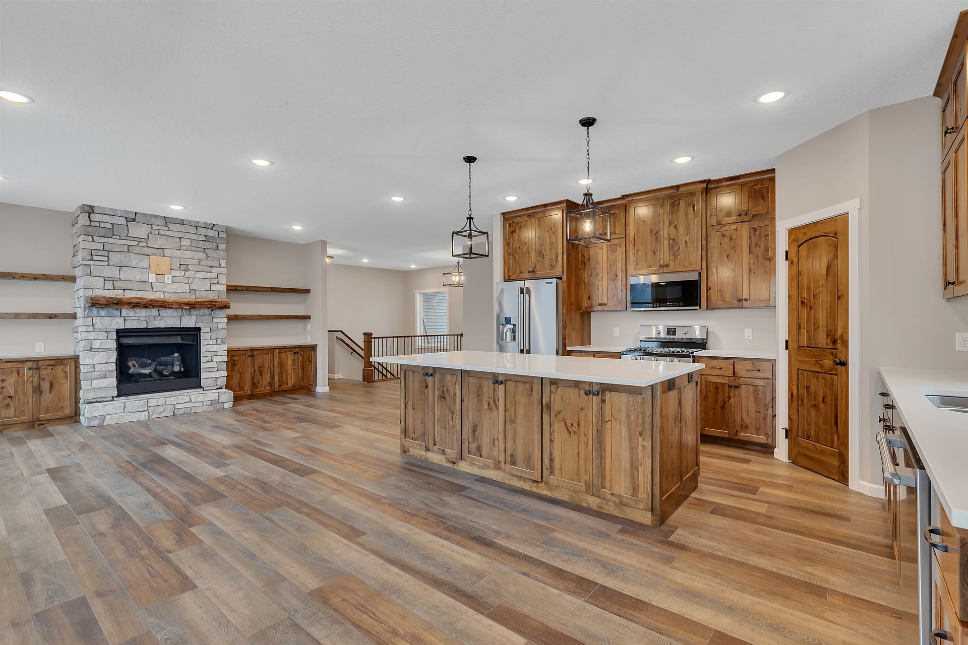 A kitchen with wooden cabinets , stainless steel appliances , a large island and a fireplace.