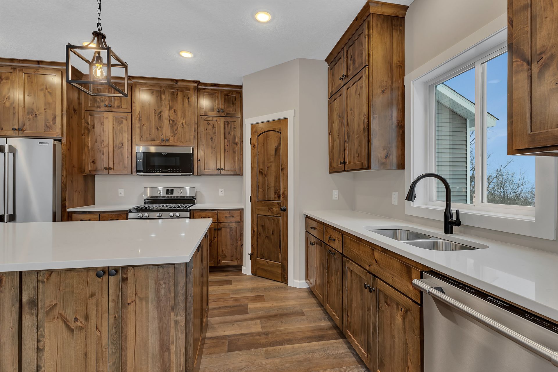 A kitchen with wooden cabinets , stainless steel appliances , a sink , and a window.