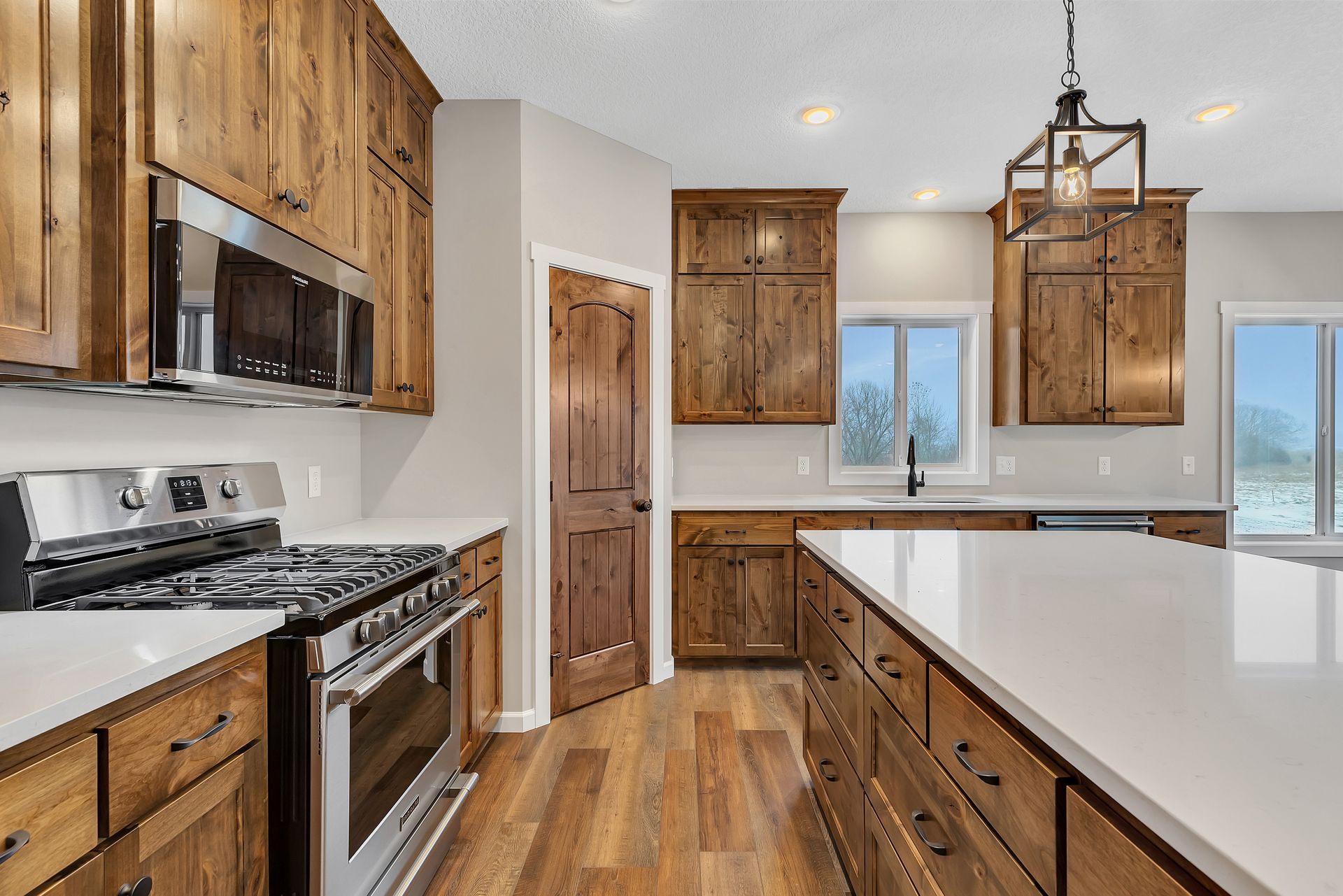 A kitchen with wooden cabinets , stainless steel appliances , and white counter tops.