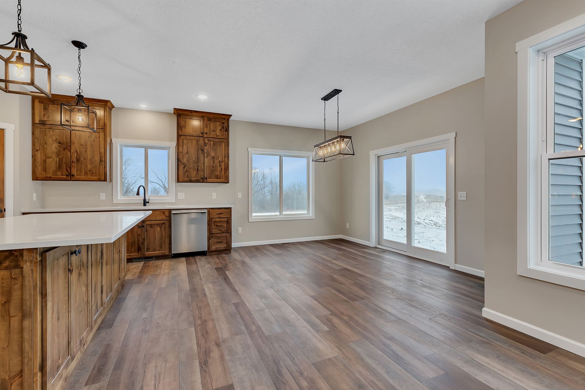 An empty kitchen with wooden cabinets and sliding glass doors.