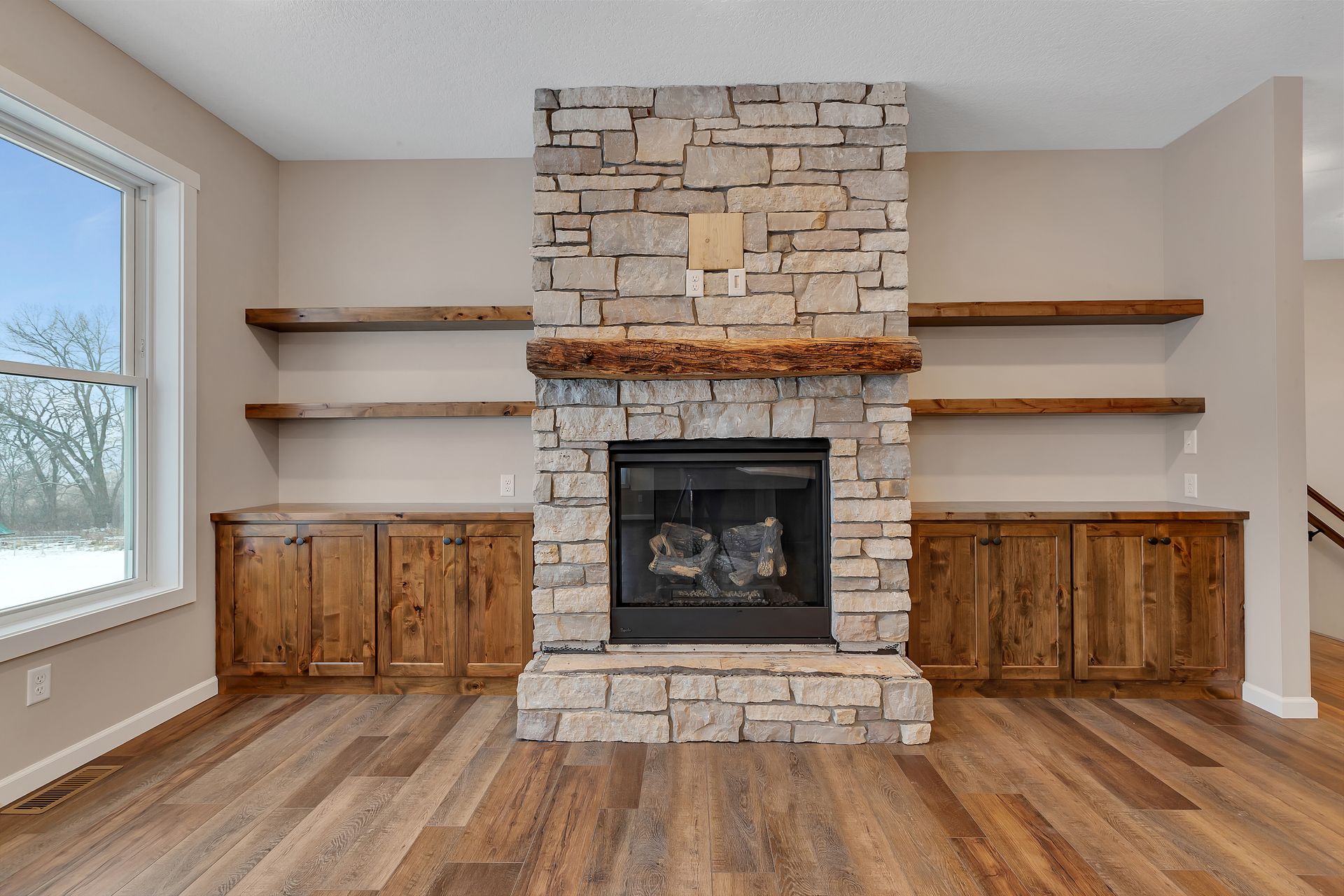 A living room with a stone fireplace and wooden shelves