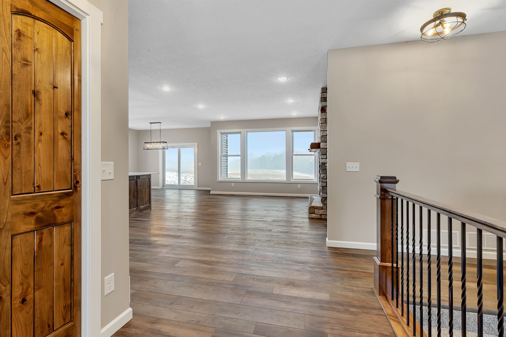 A hallway in a house with hardwood floors and a staircase leading to the second floor.