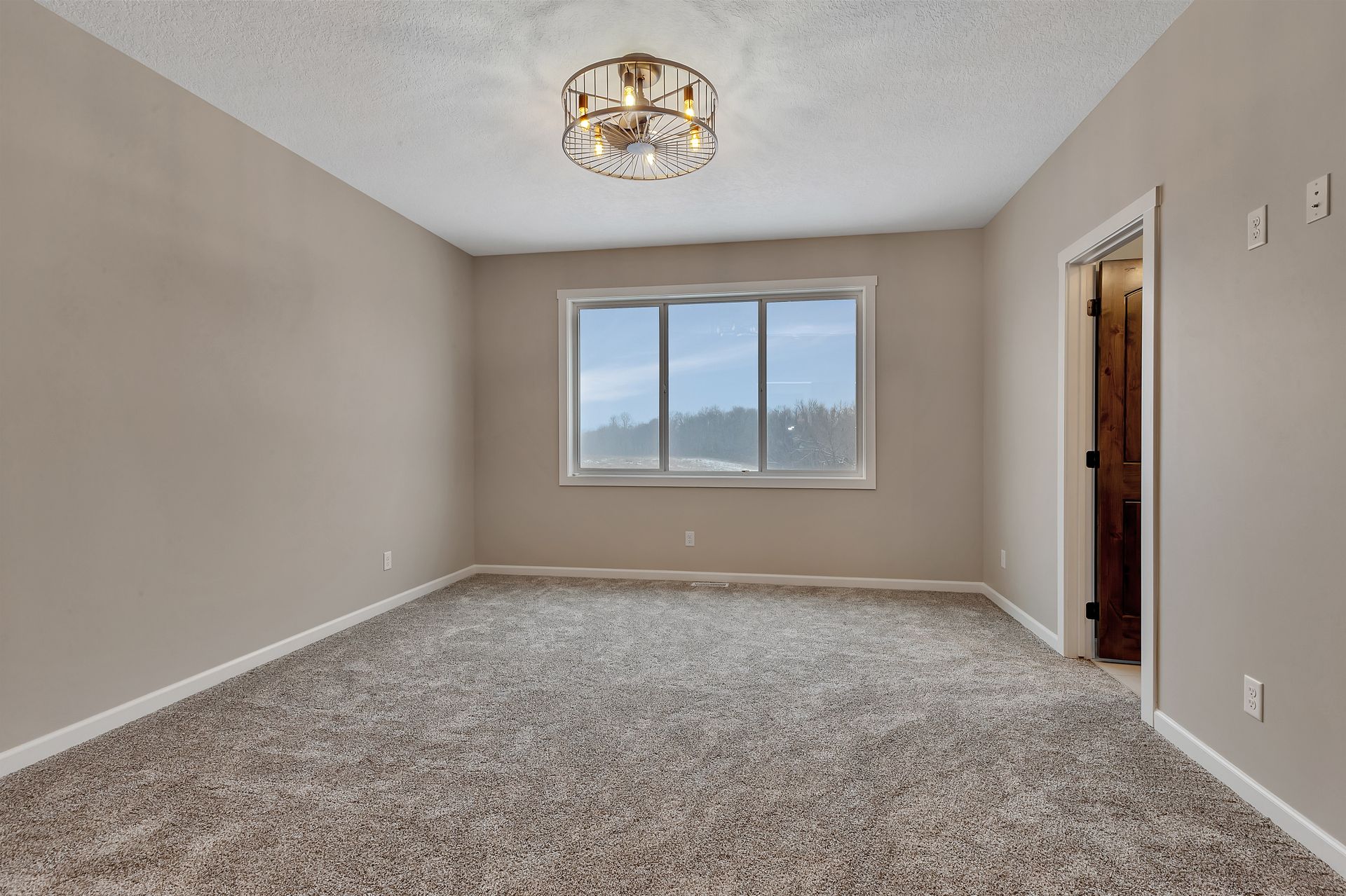 An empty room with a large window and a chandelier.