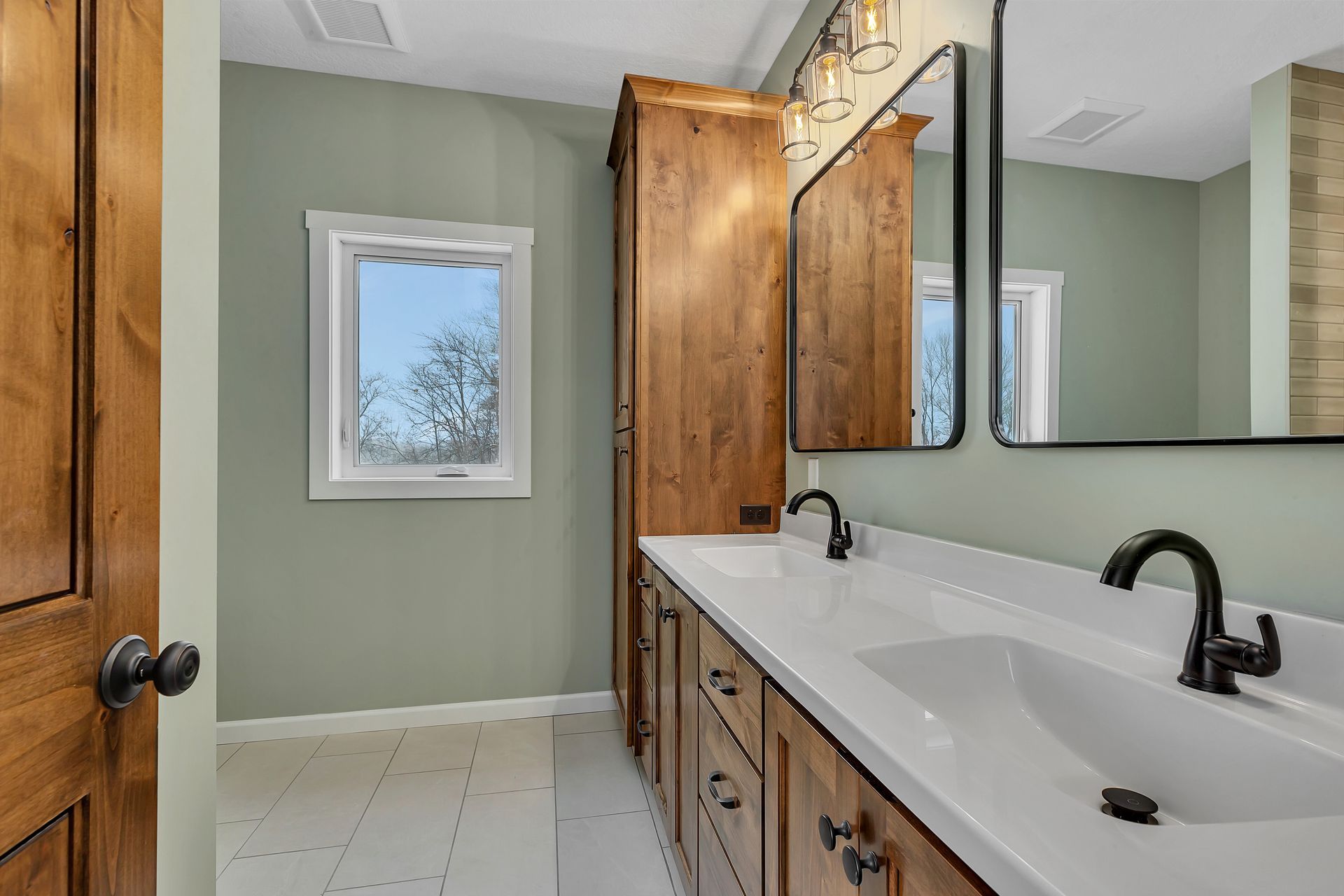A bathroom with two sinks , a mirror and a window.