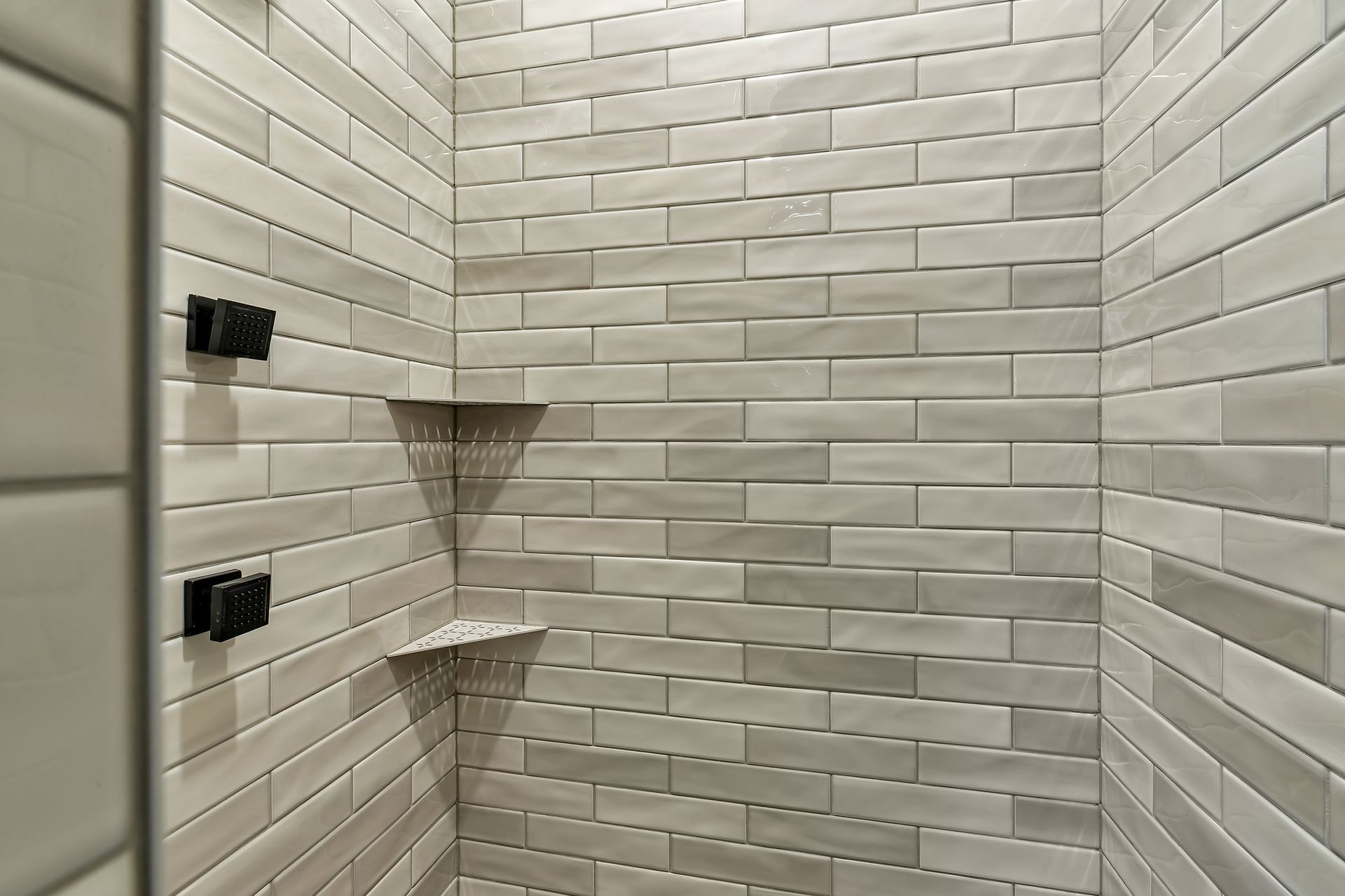 A shower with a brick wall and a corner shelf.
