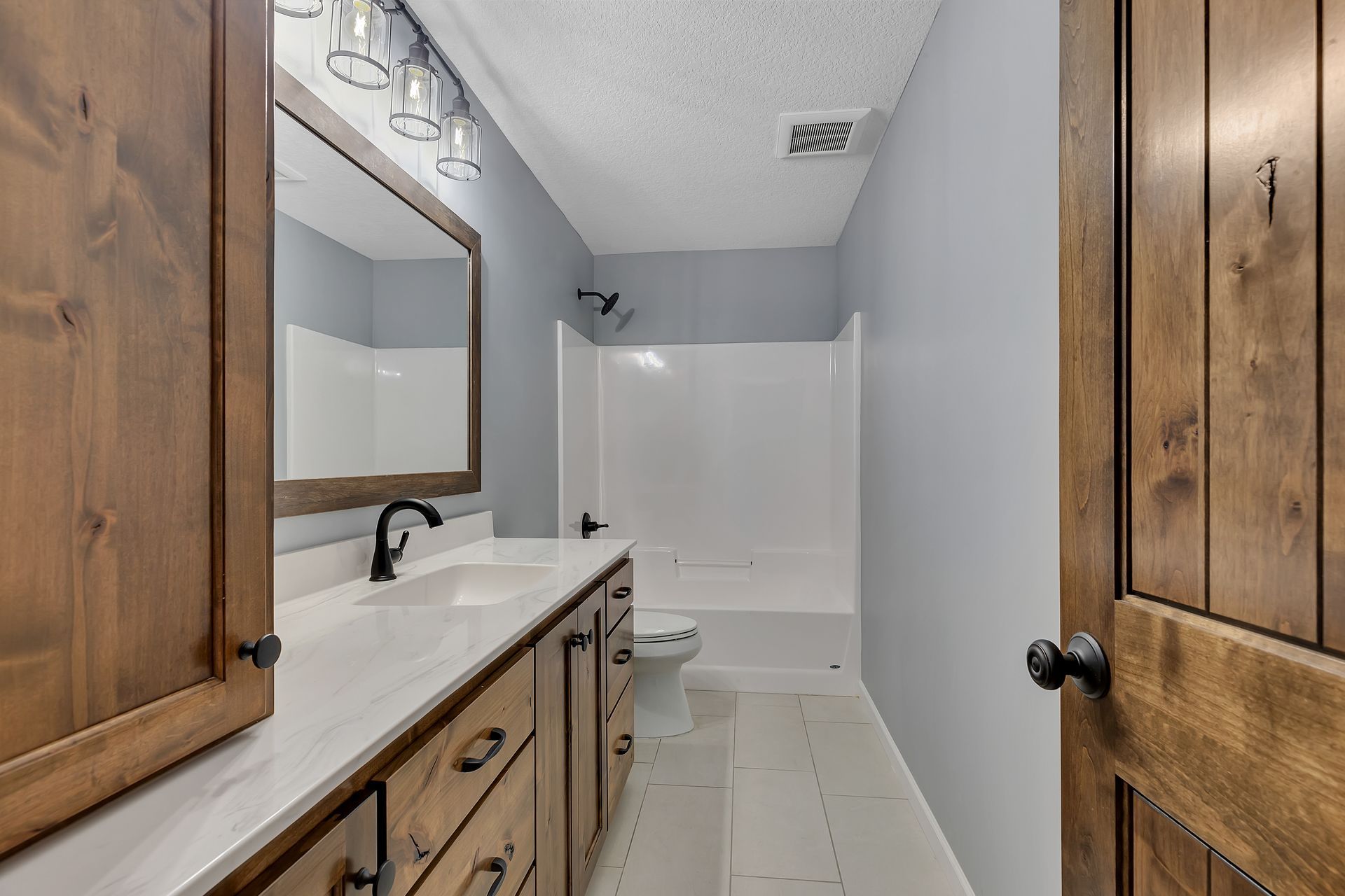 A bathroom with a sink , toilet , mirror and shower.