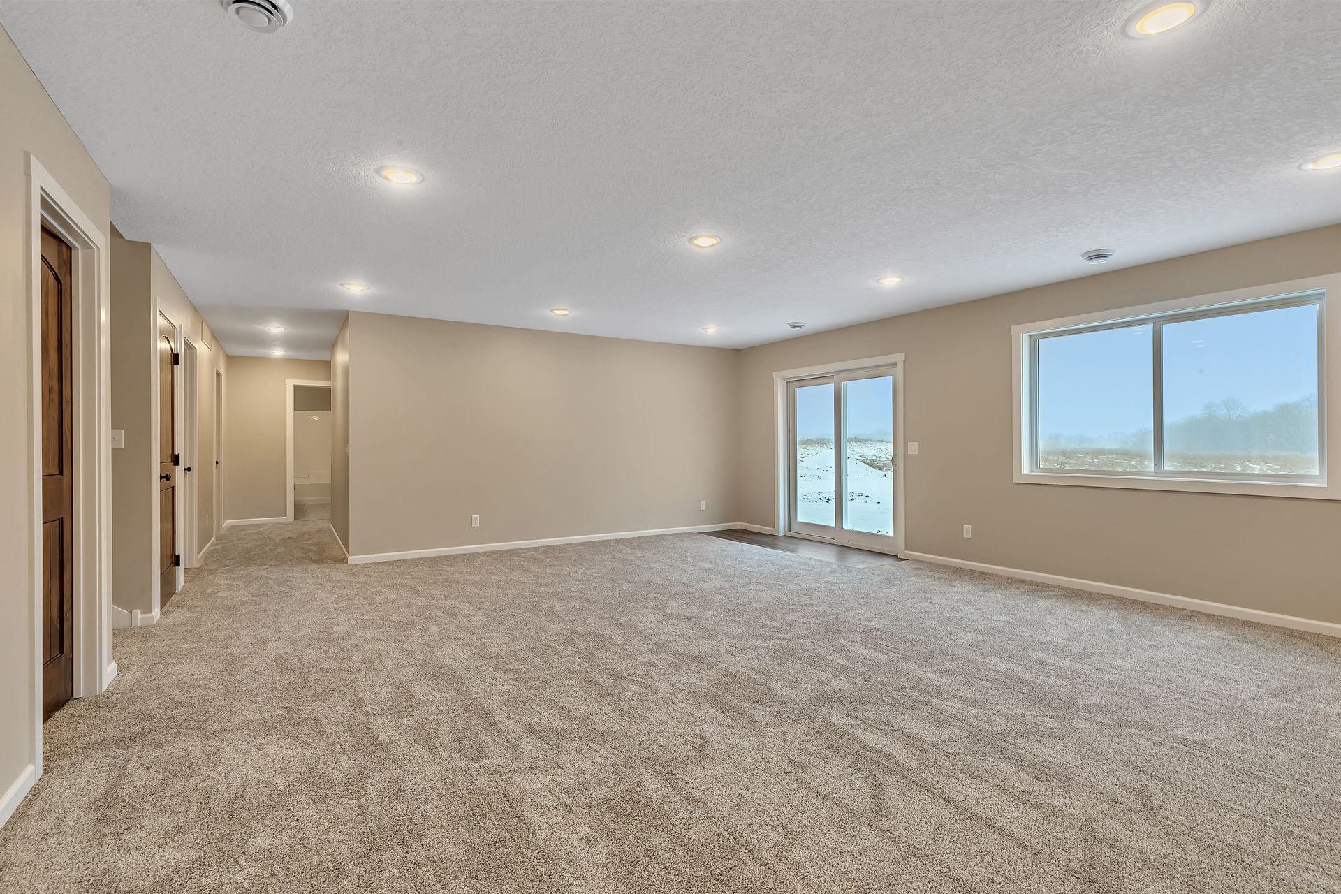 An empty basement with a lot of windows and carpet.