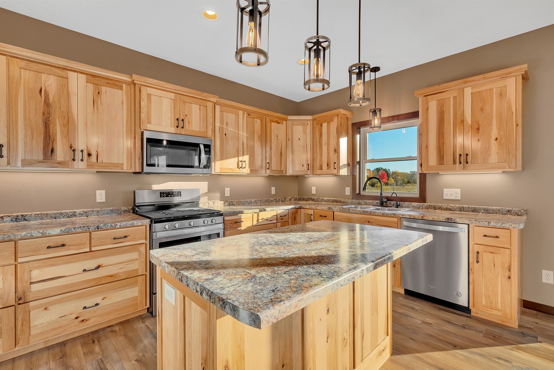 A kitchen with wooden cabinets , granite counter tops , stainless steel appliances and a large island.