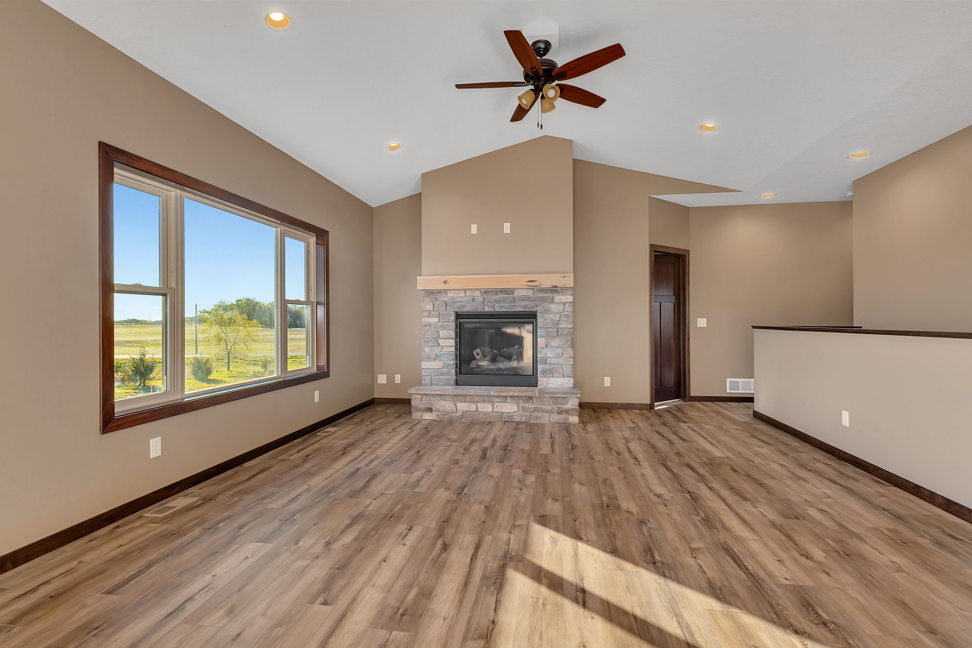 An empty living room with a fireplace and ceiling fan.