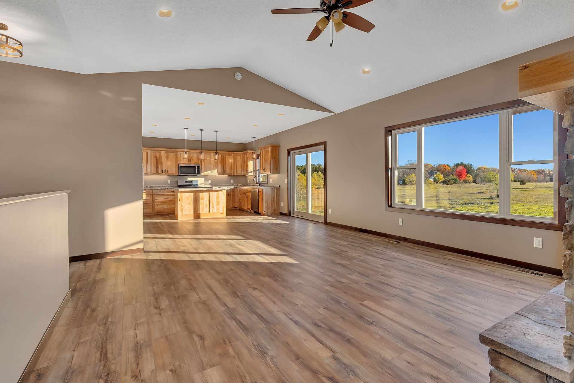 An empty living room with hardwood floors and a ceiling fan.