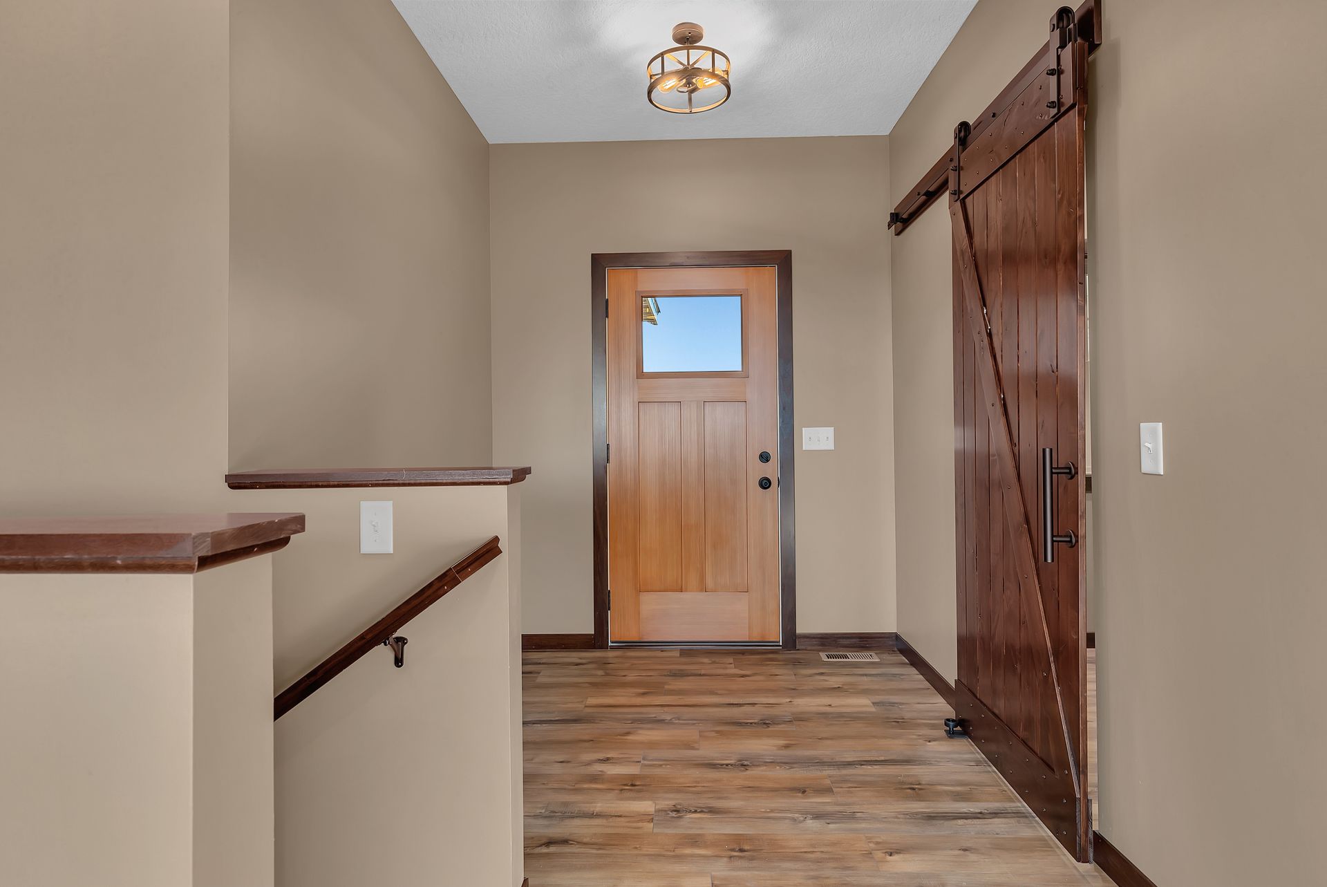 A hallway with a wooden door and a sliding barn door.
