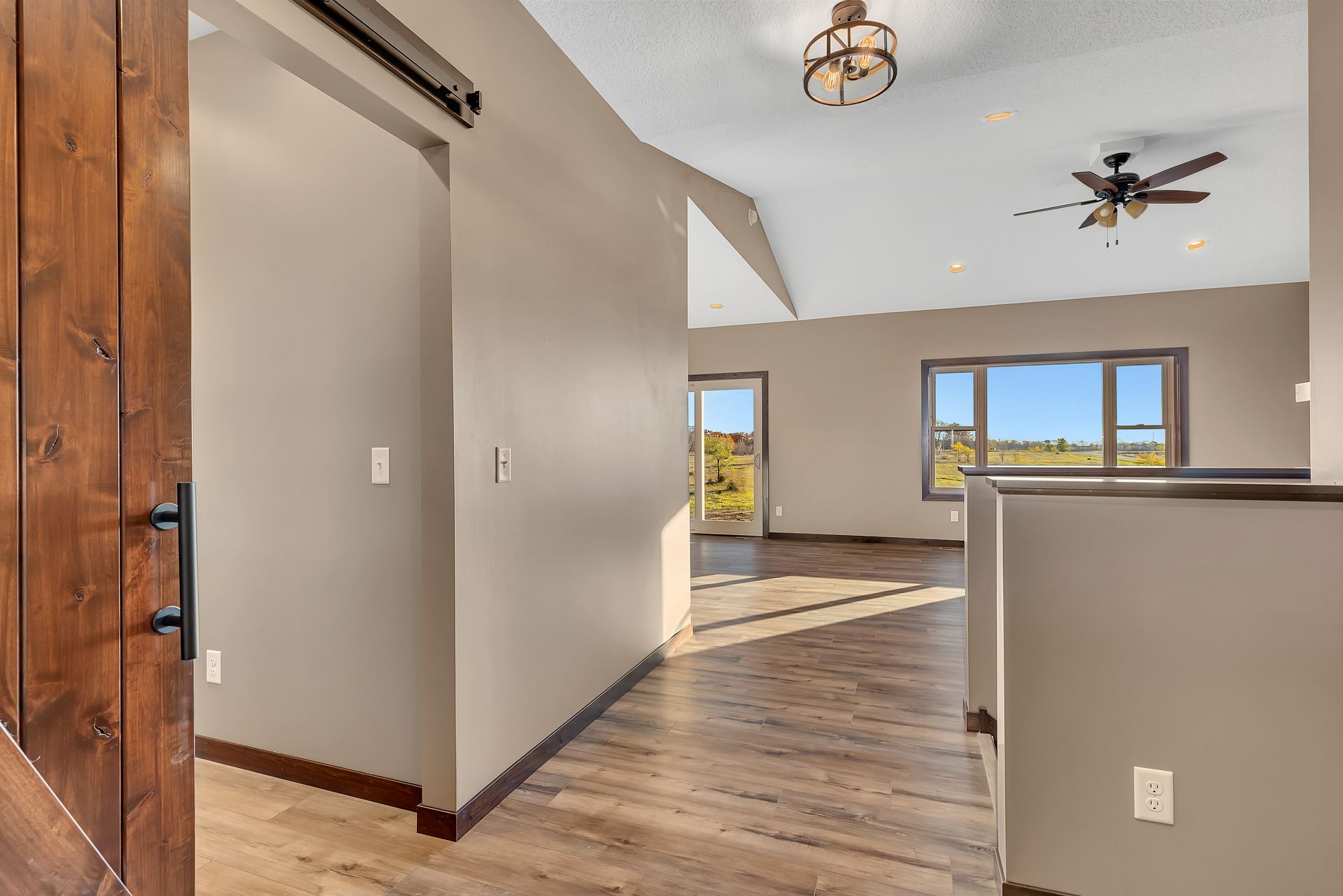 A hallway in a house with hardwood floors and a ceiling fan.