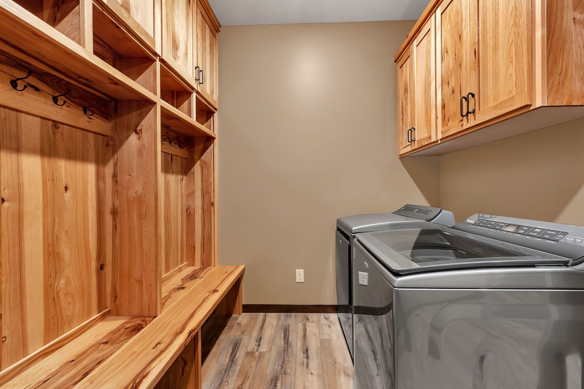 A laundry room with a washer and dryer and wooden cabinets.
