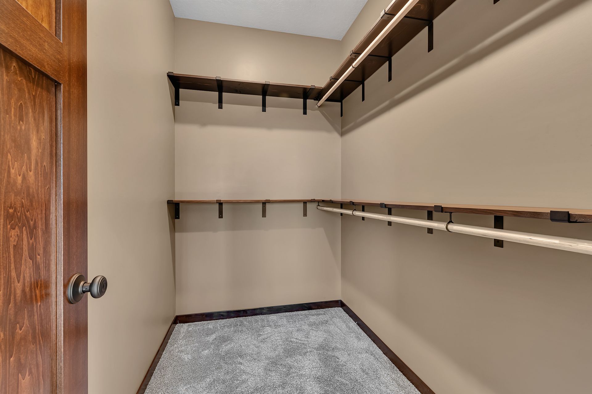 A walk in closet with a wooden door and shelves.