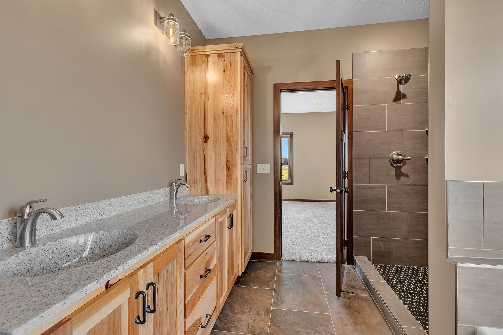 A bathroom with two sinks and a walk in shower.