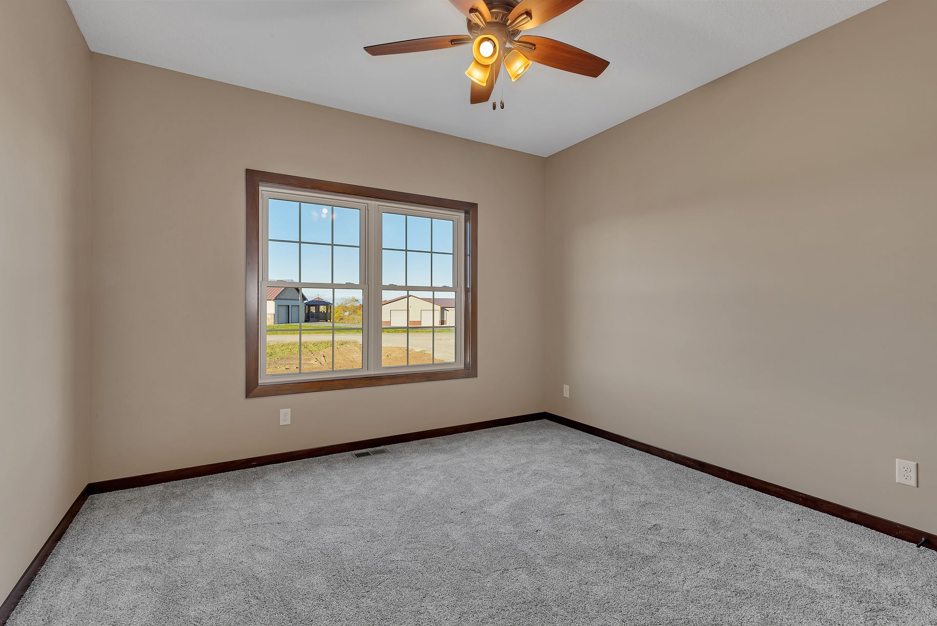 An empty bedroom with a ceiling fan and a window.