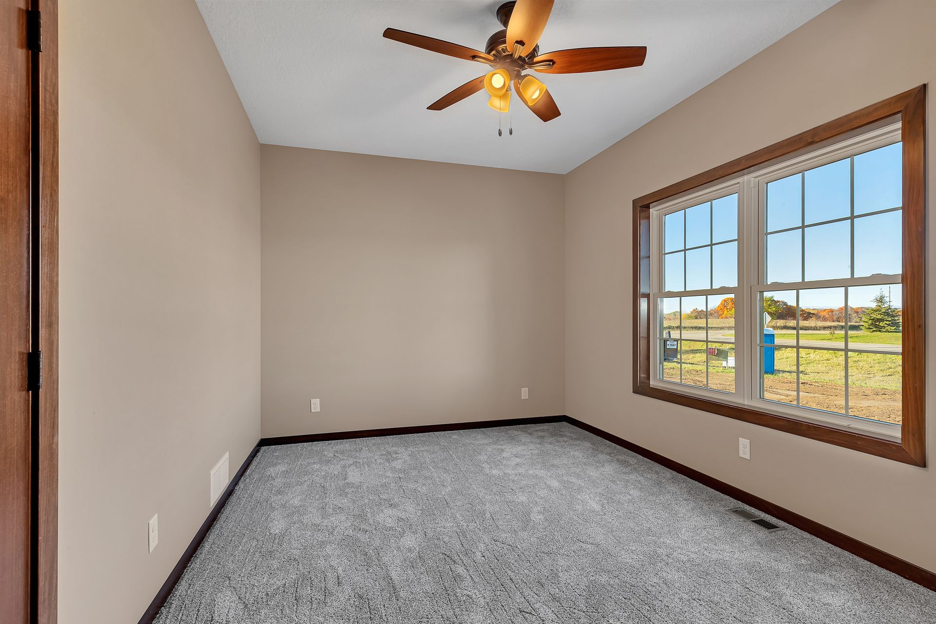 An empty bedroom with a ceiling fan and two windows.