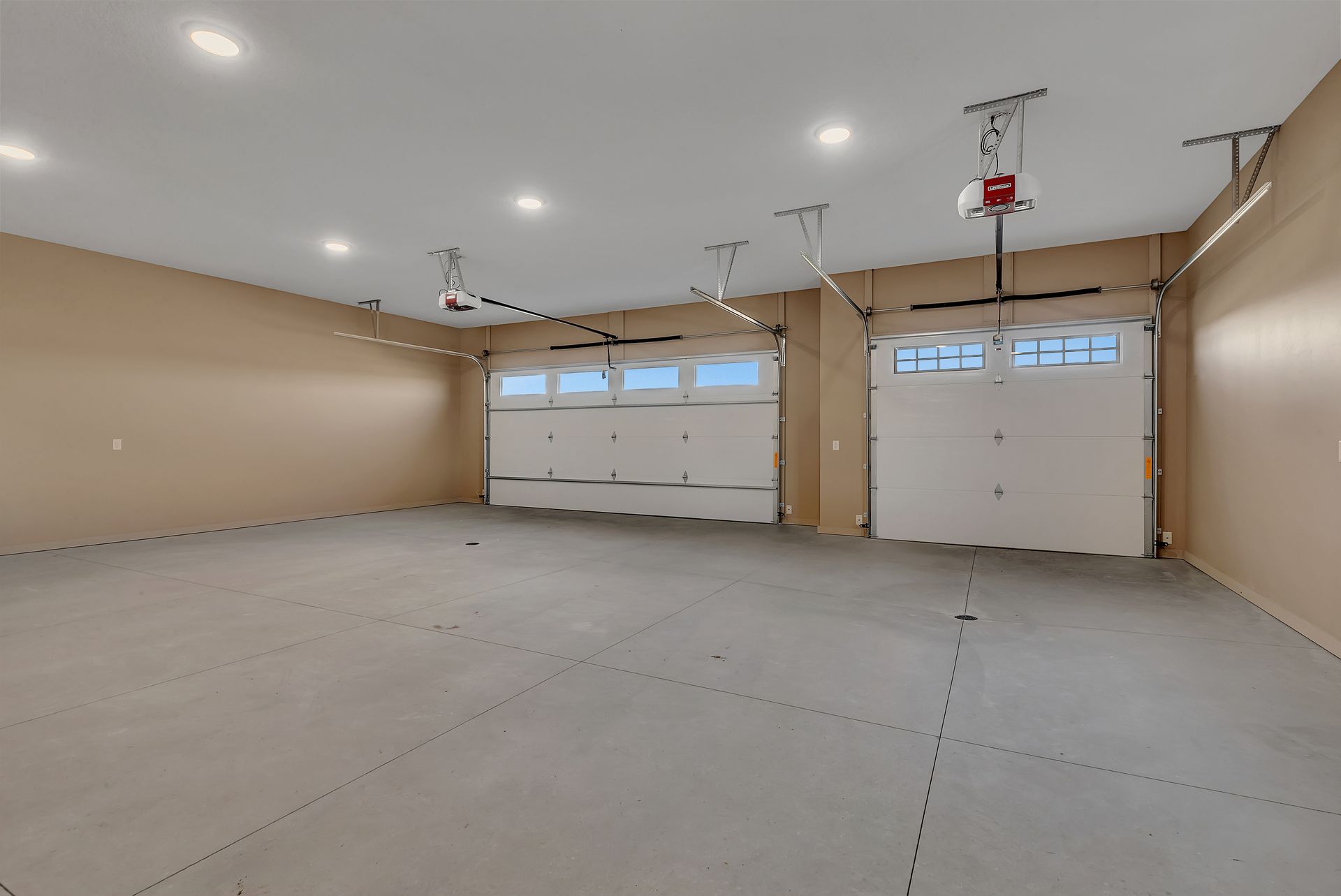 A large empty garage with two garage doors and a ceiling fan.