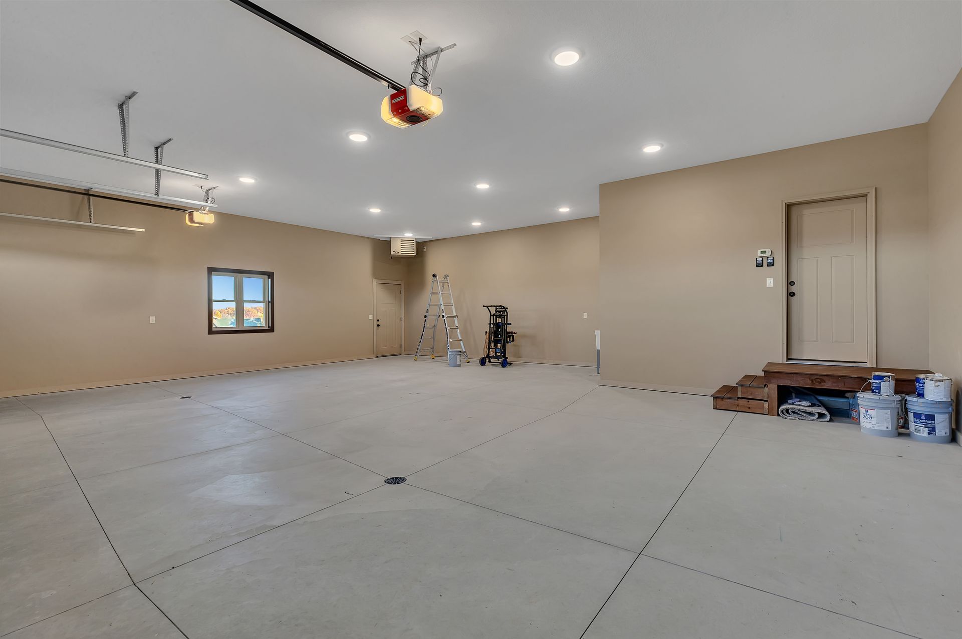 A large empty garage with a ladder and a window.