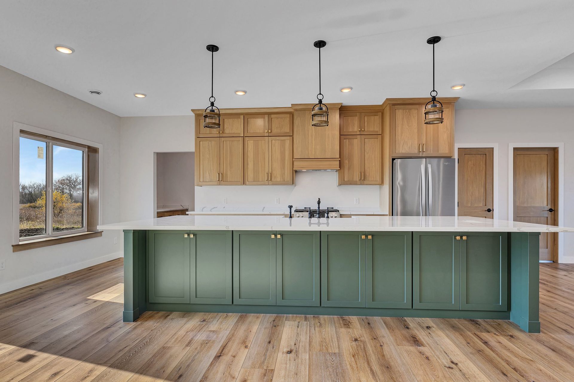 A kitchen with green cabinets and a large island.