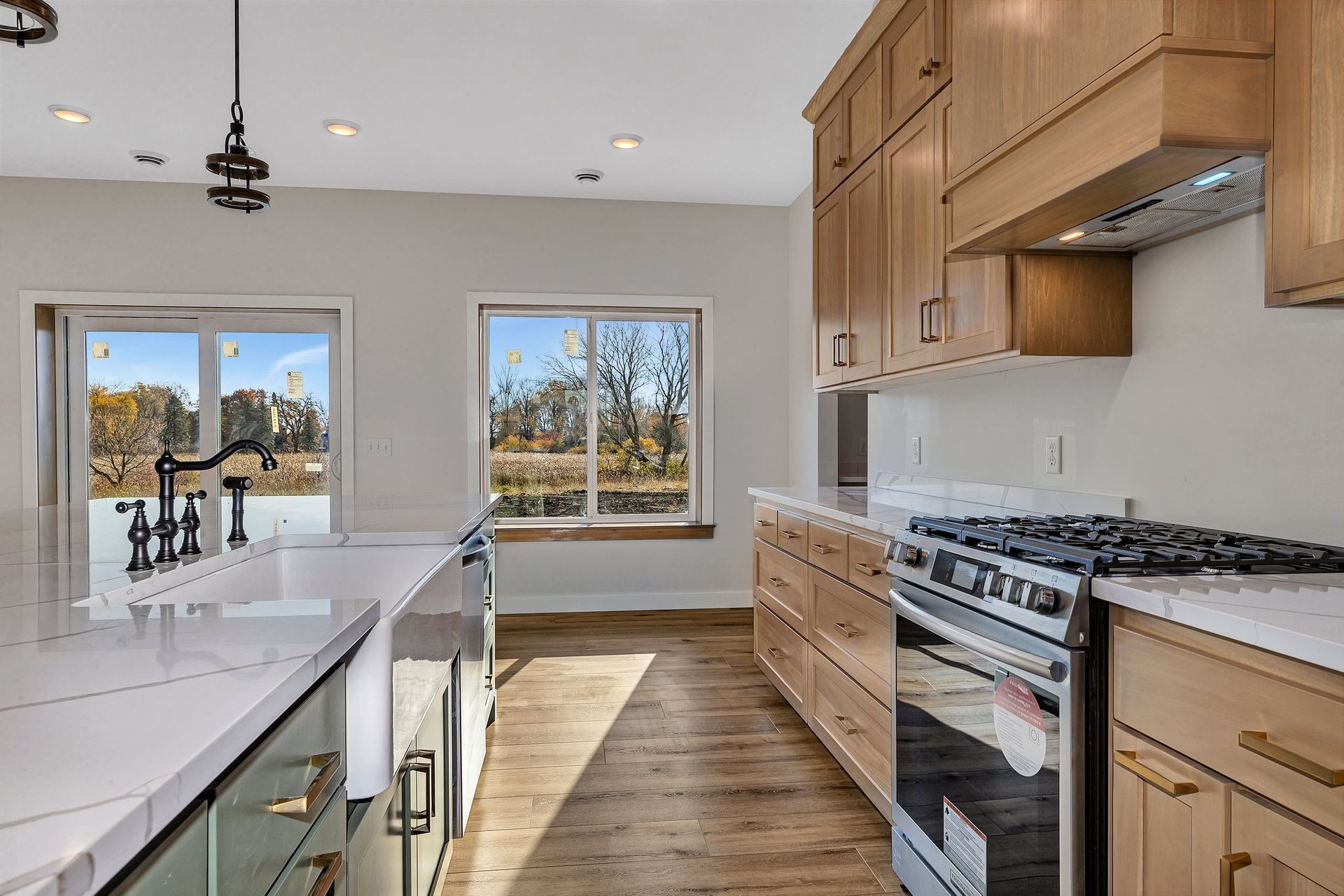 A kitchen with wooden cabinets , a stove , a sink , and a lot of windows.