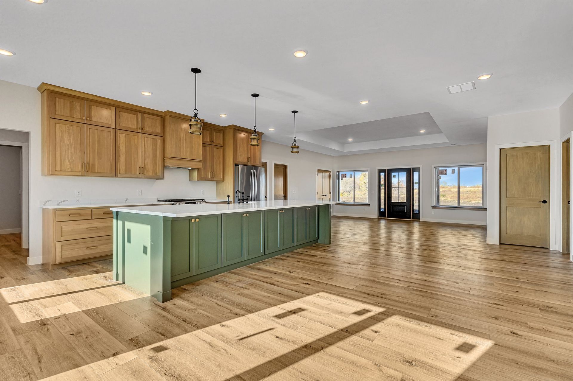 A large empty kitchen with green cabinets and hardwood floors.