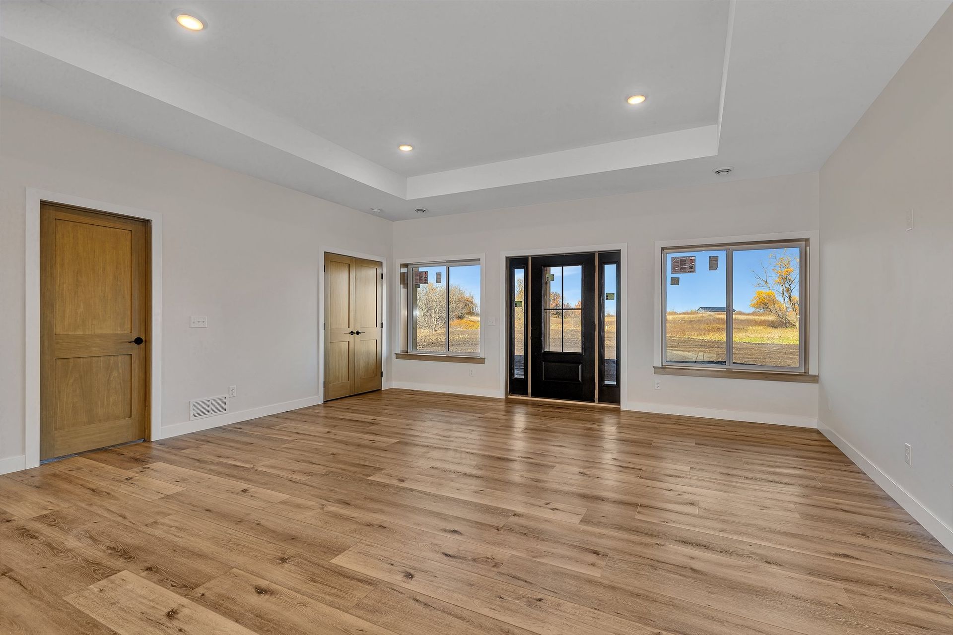 An empty living room with hardwood floors and white walls.