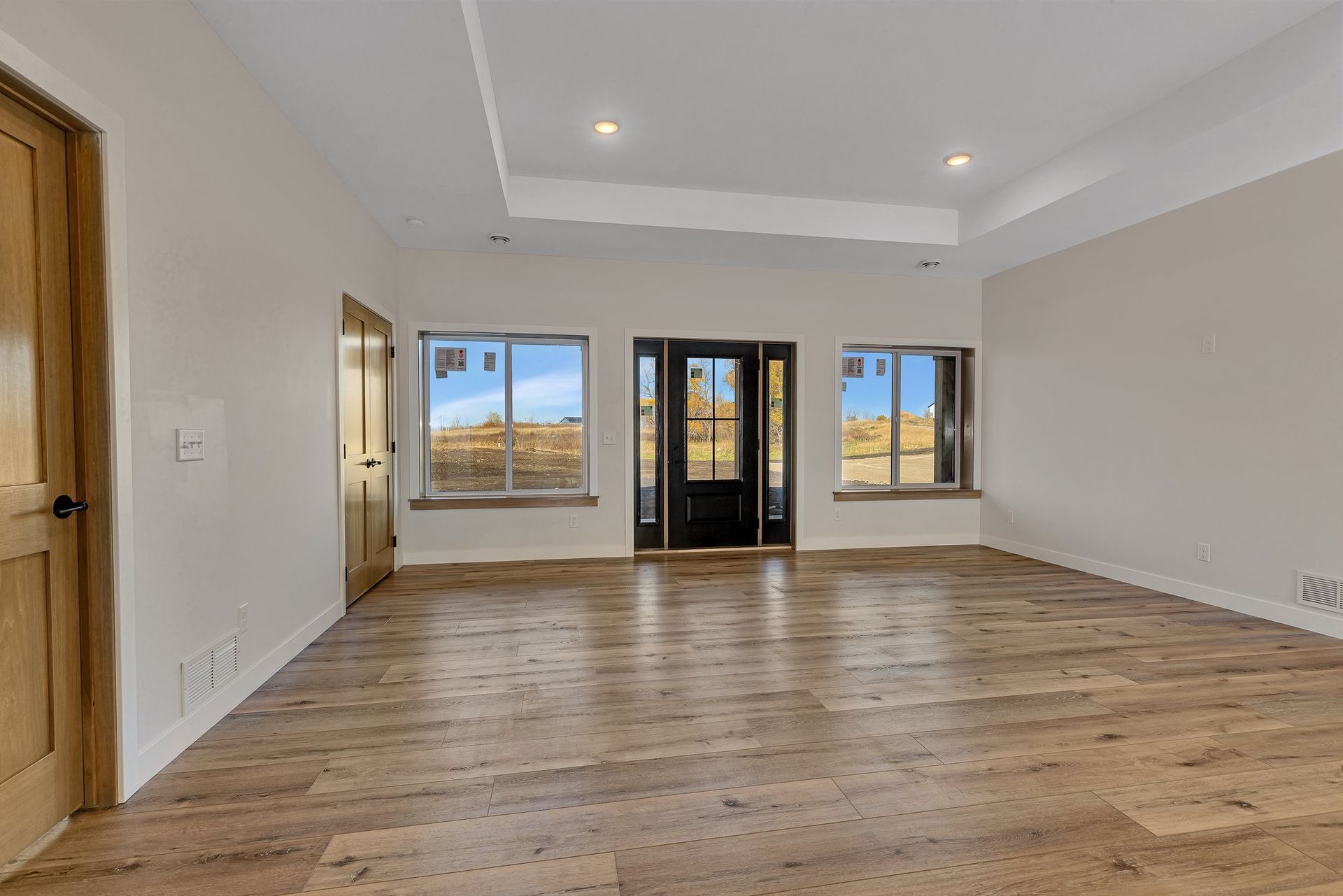 An empty living room with hardwood floors and white walls.