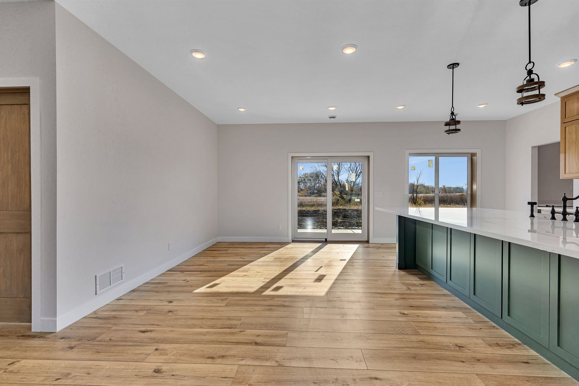 A large empty room with hardwood floors and sliding glass doors.