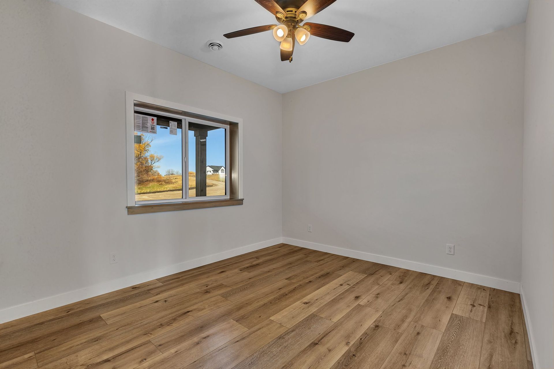 An empty room with hardwood floors and a ceiling fan.
