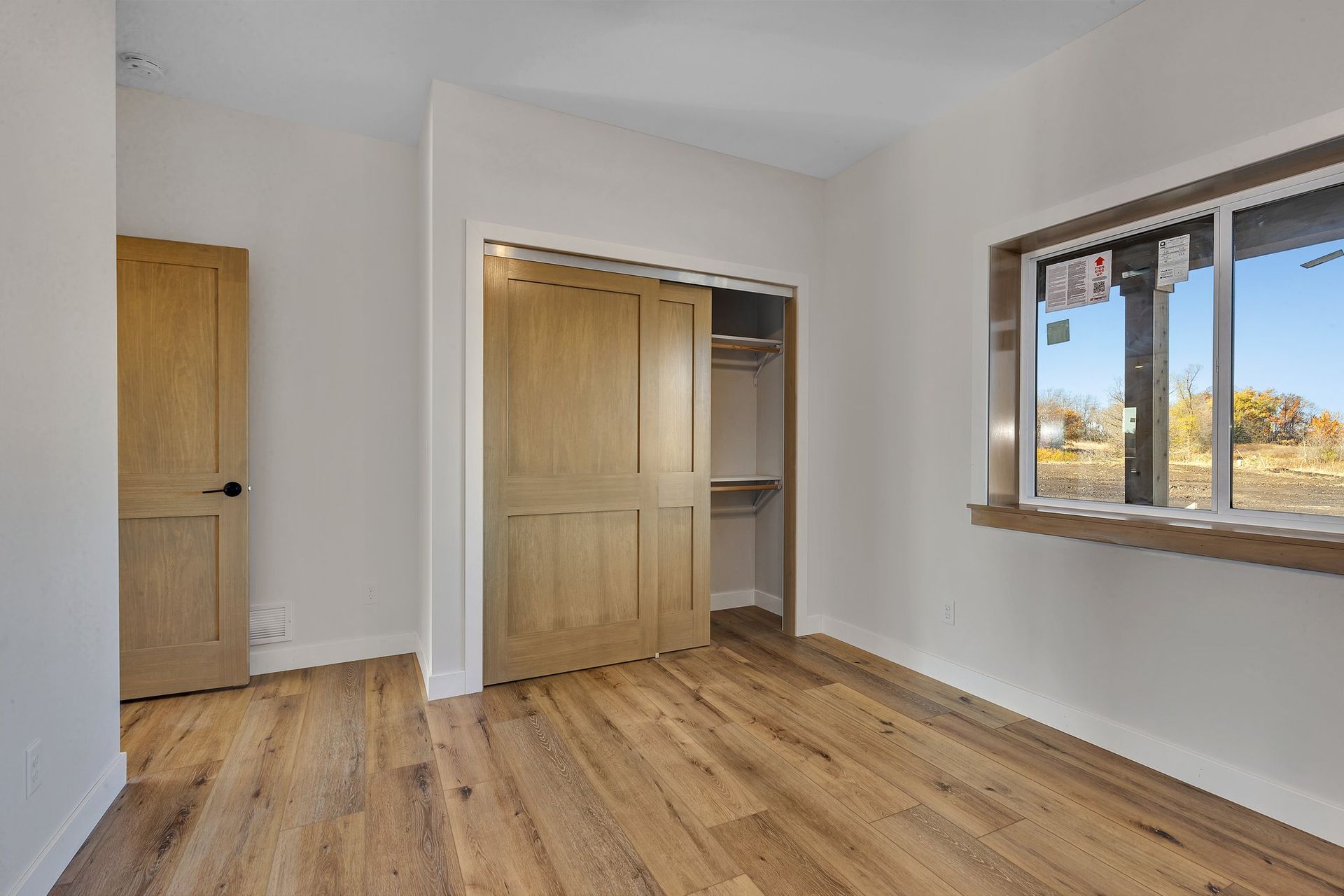An empty room with hardwood floors , a closet and a window.