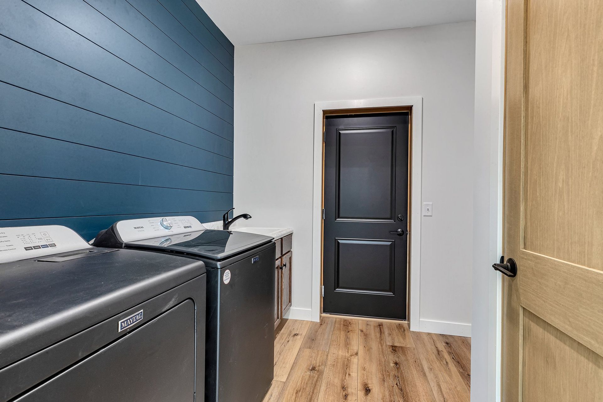 A laundry room with a washer and dryer and a black door.