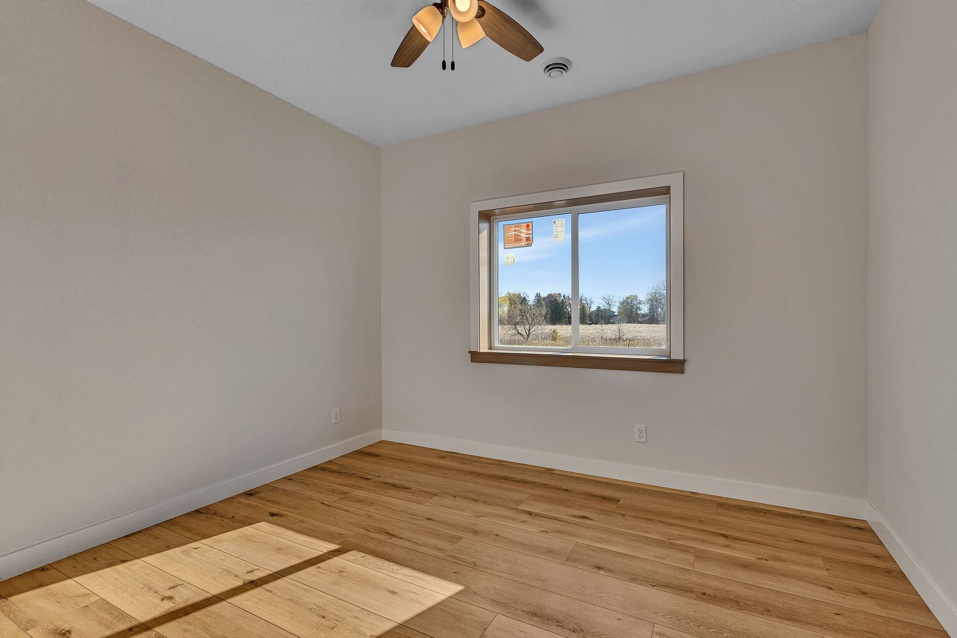 An empty room with a ceiling fan and a window.