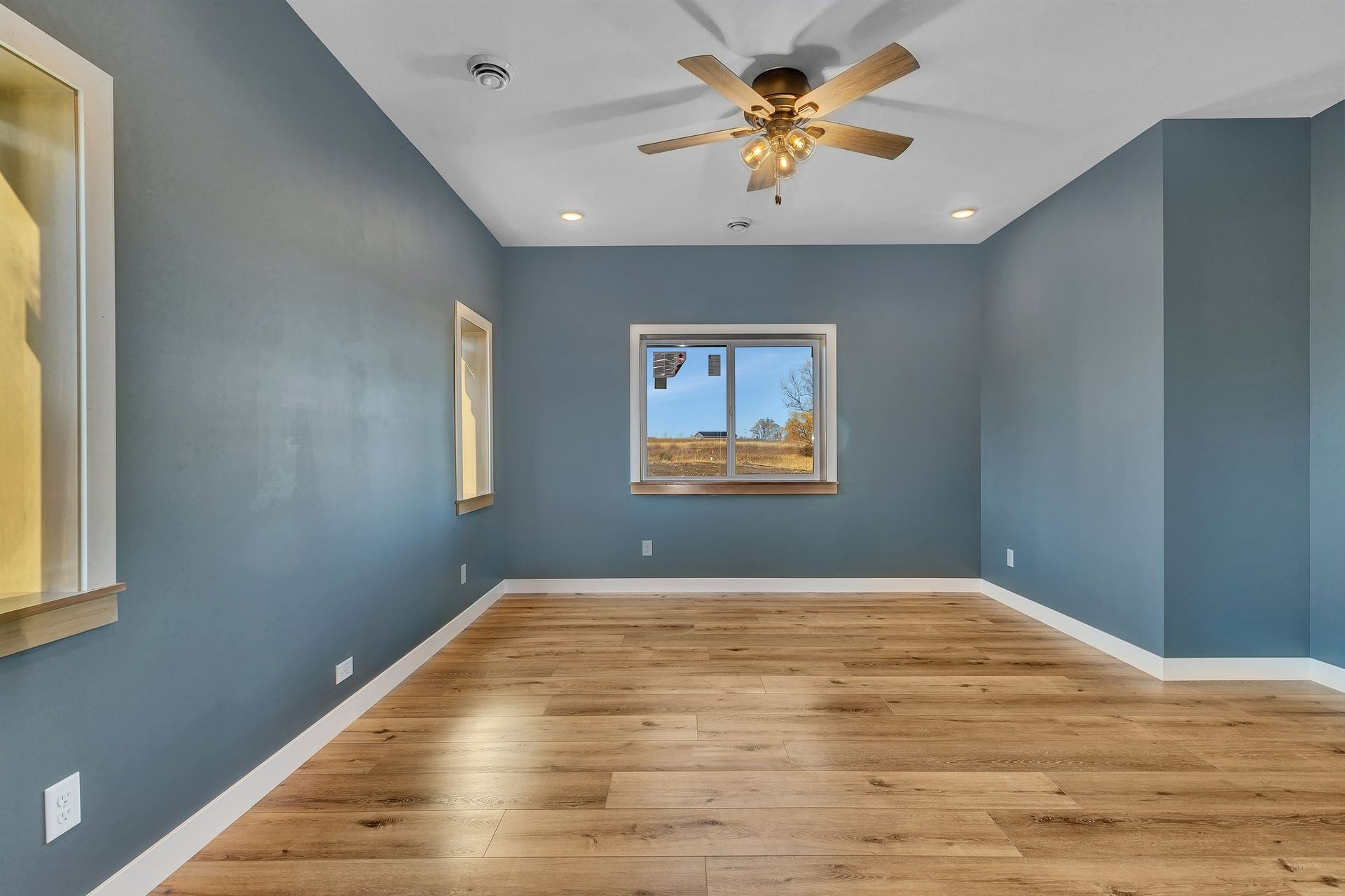 An empty room with a ceiling fan and a window