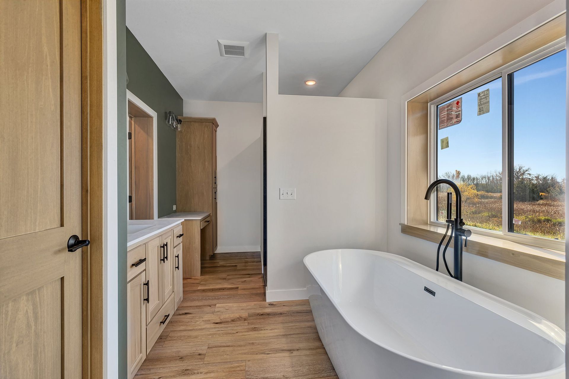 A bathroom with a tub , sink , and window.