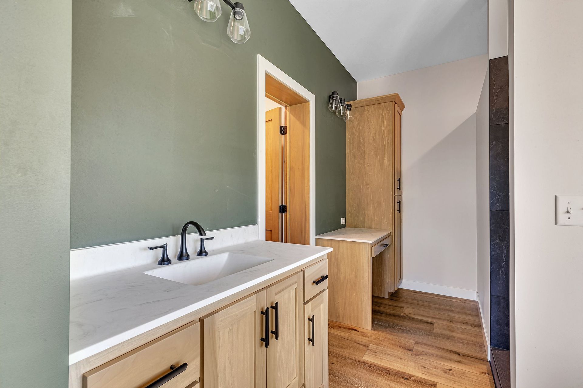 A bathroom with a sink , cabinets , and wooden floors.