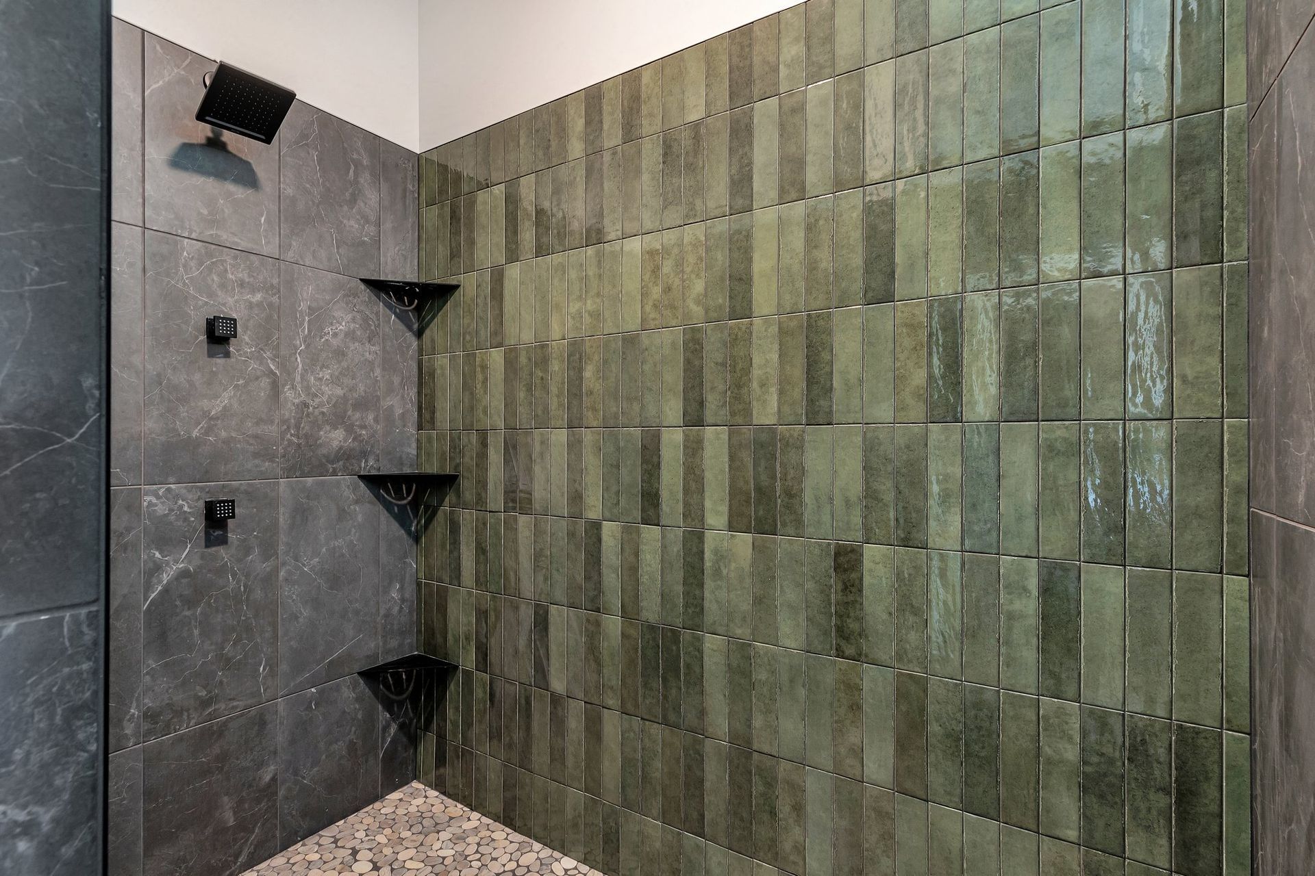 A bathroom with green tiles and a walk in shower.