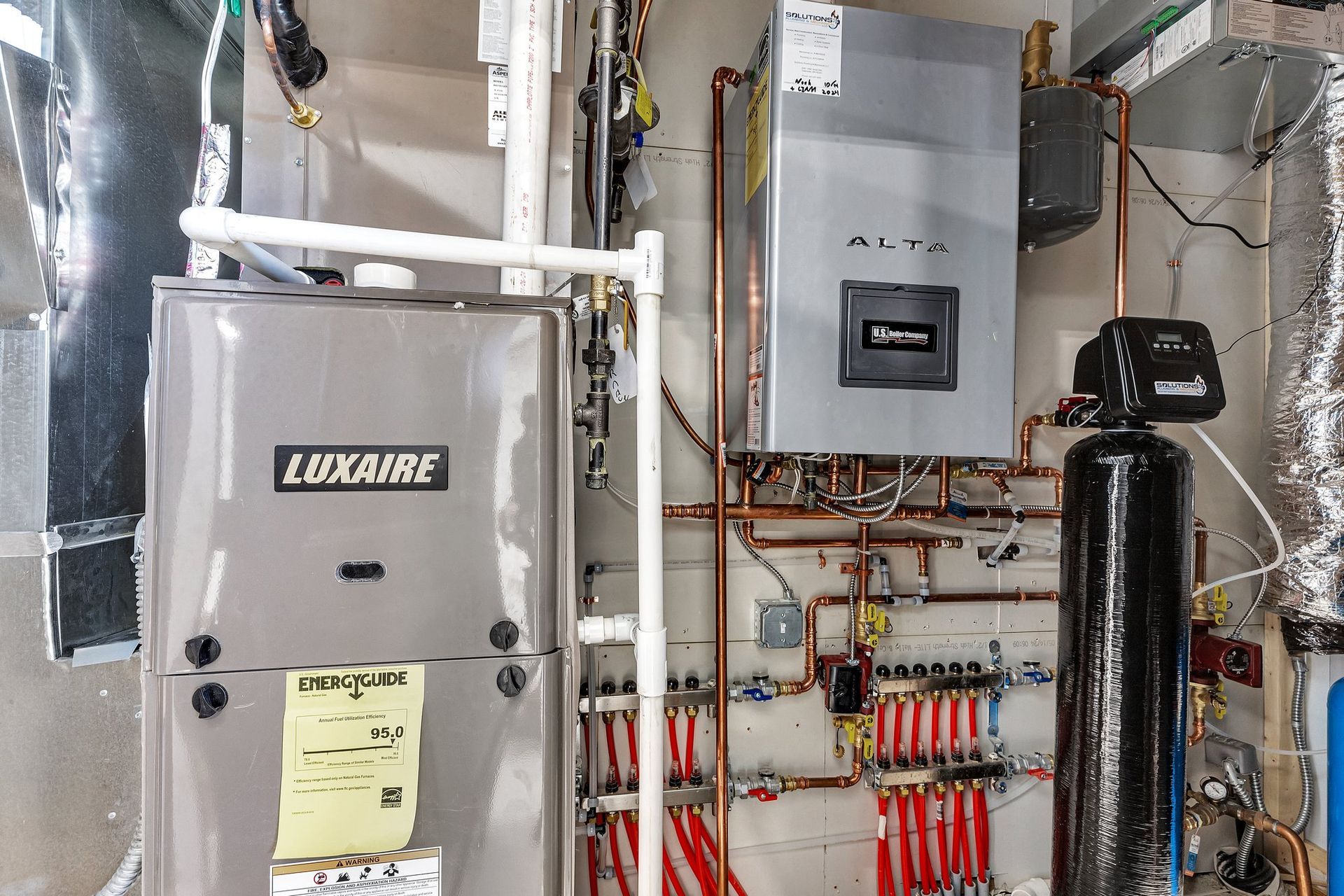 A luxaire boiler is sitting in a room with a lot of pipes.