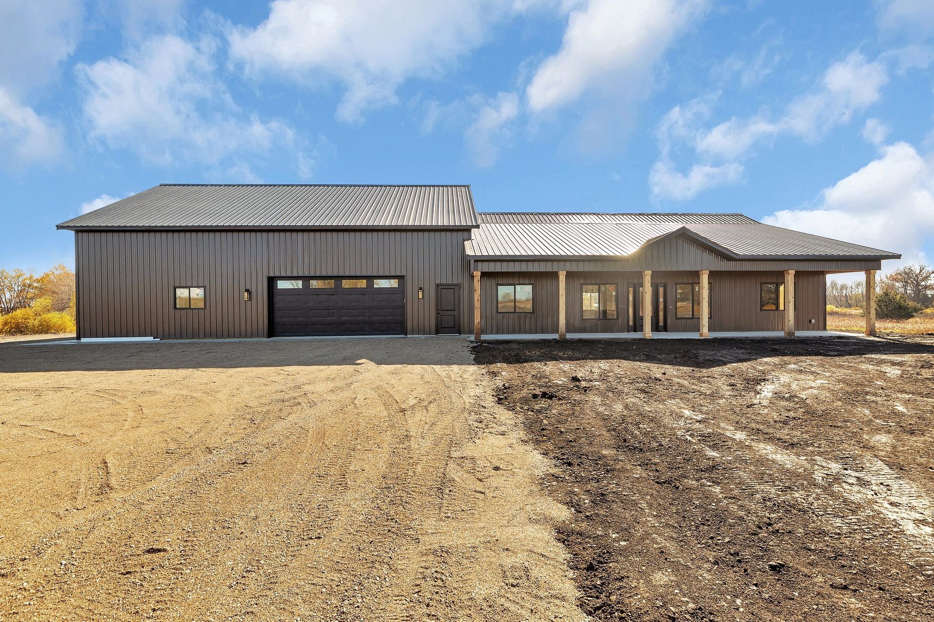 A large house is sitting in the middle of a dirt field.