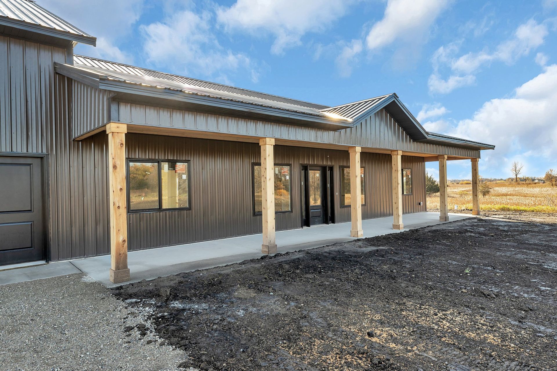 A large metal building with a porch and a garage.